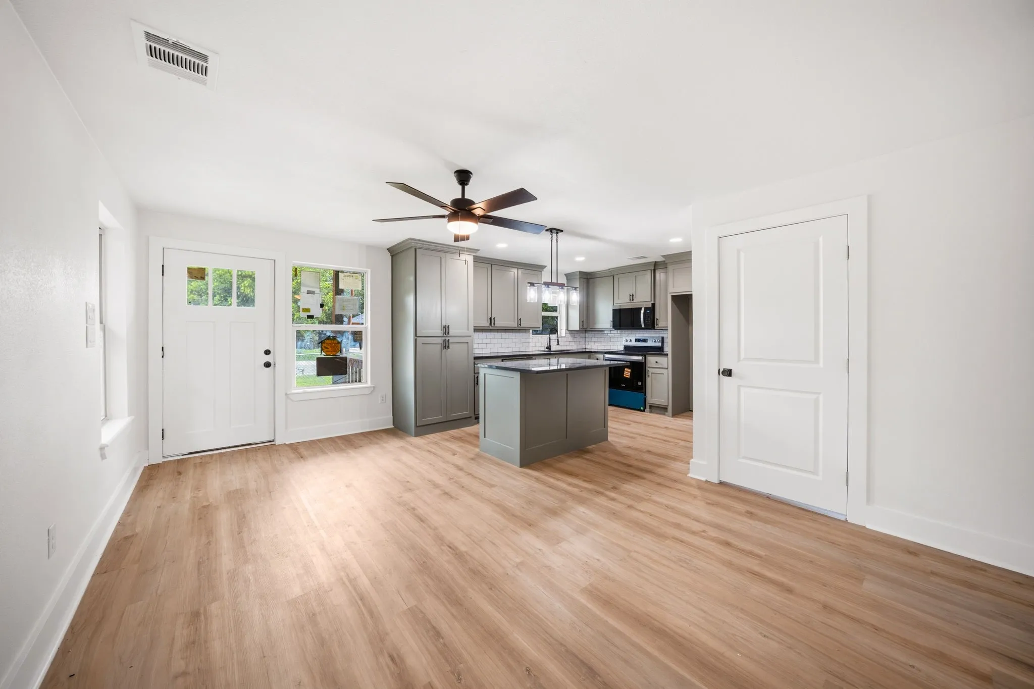 Open-concept living space featuring wood-finish flooring, a modern ceiling fan, and recessed lighting