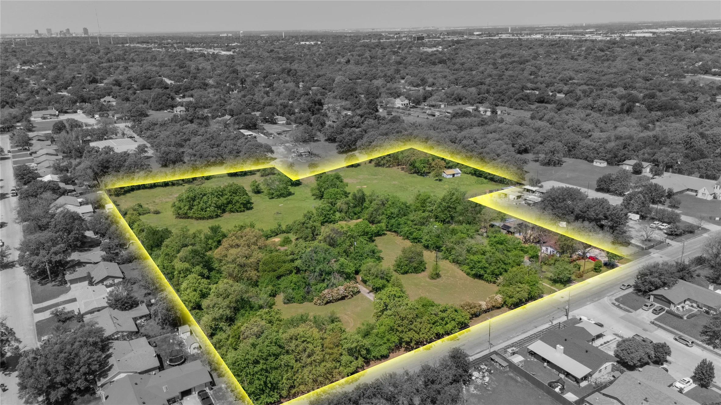 Expansive land parcel featuring a mix of open green spaces and mature trees