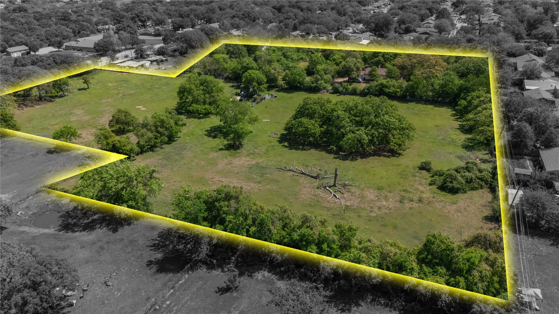 Expansive land parcel featuring a perimeter of mature trees and open grassy areas