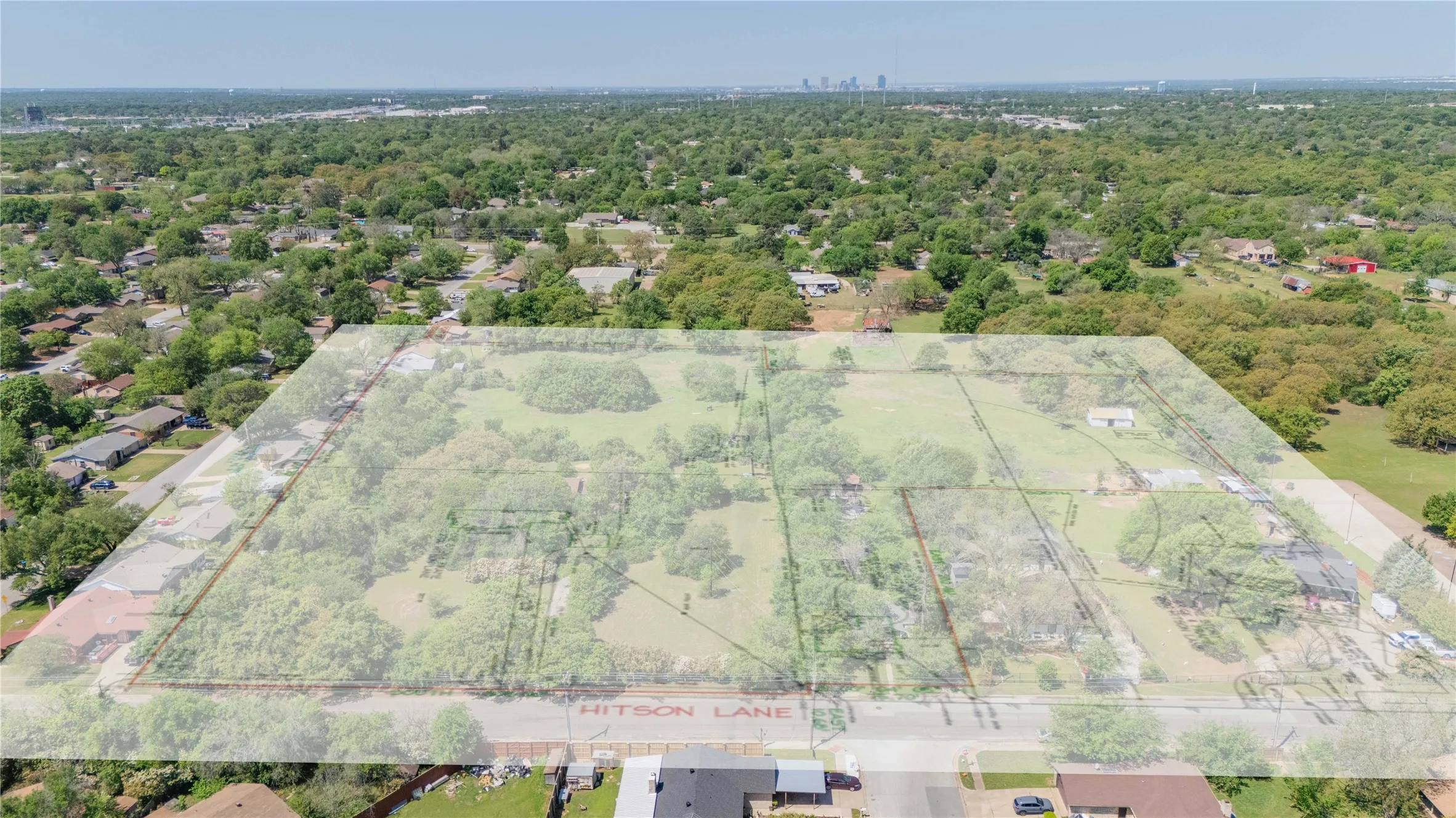 Expansive land parcel featuring multiple delineated sections, surrounded by mature trees
