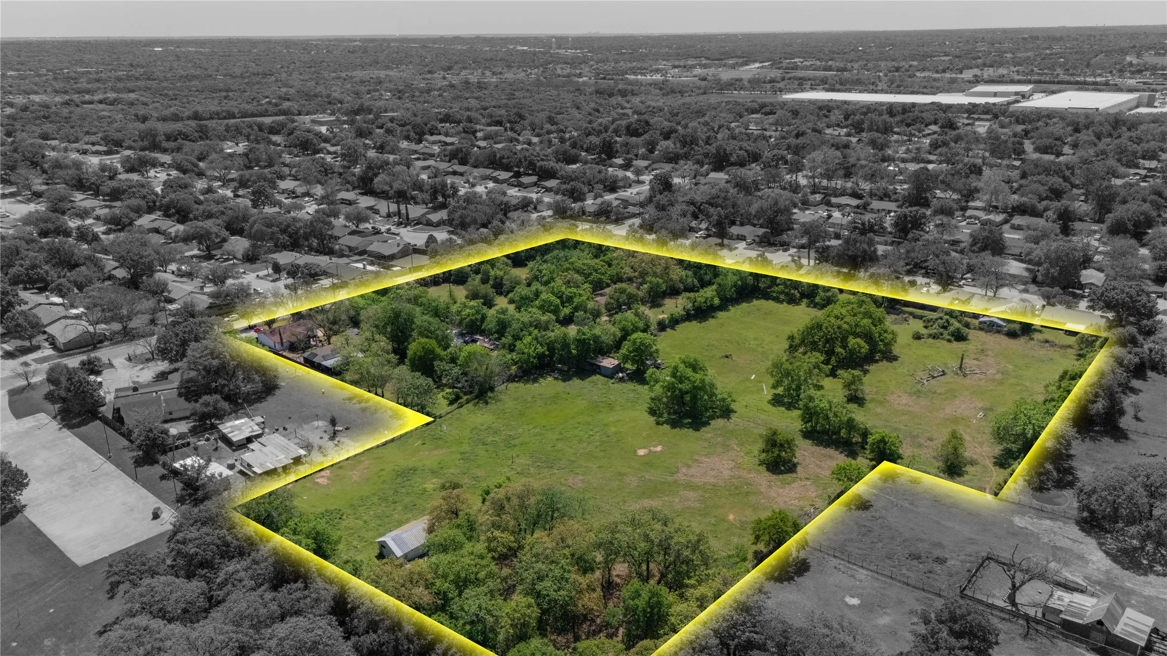 Expansive land parcel featuring a substantial tree canopy, open grassy areas, a visible structure, and a defined perimeter