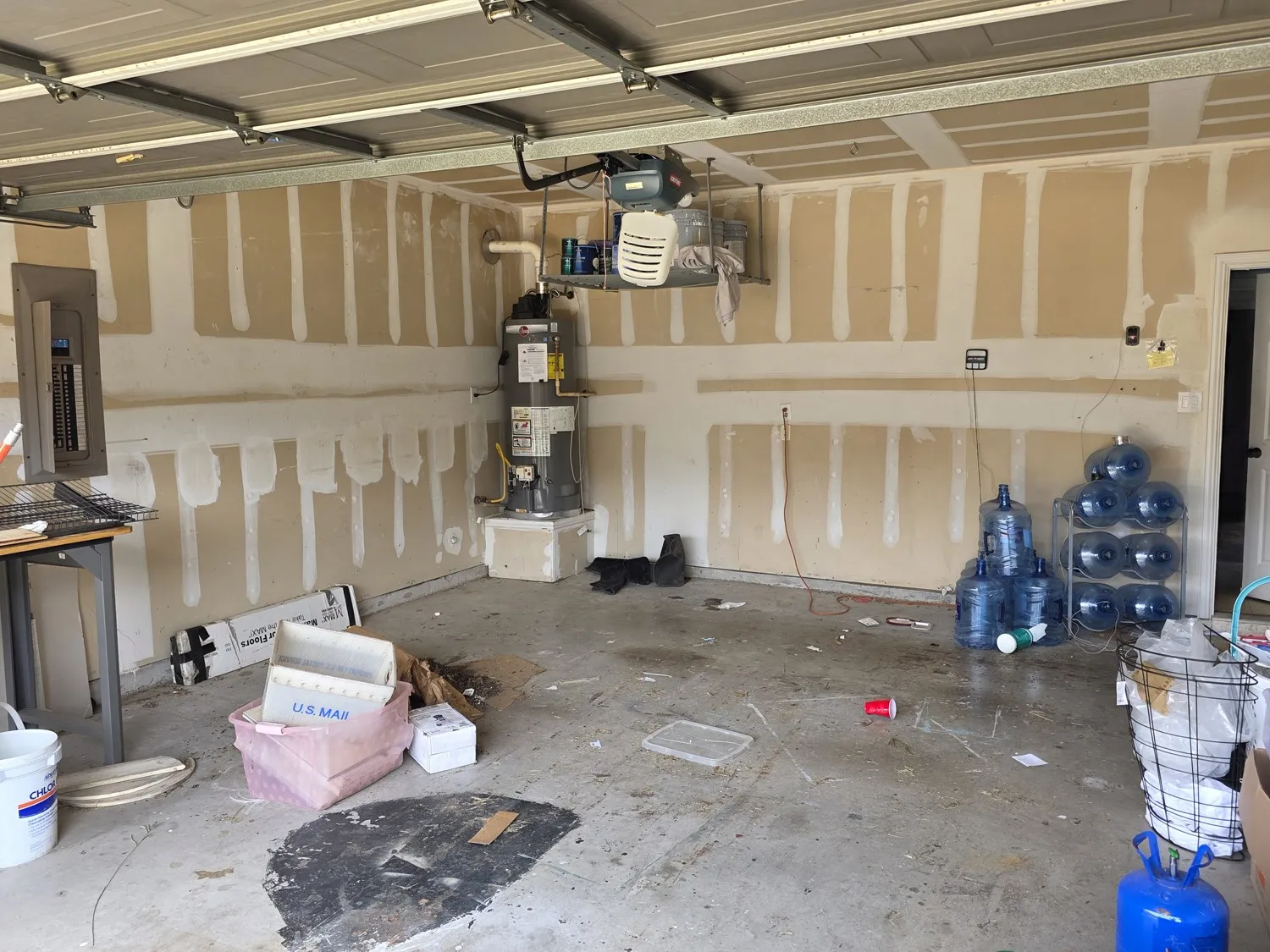 Utility room featuring a water heater, electrical panel, and unfinished walls