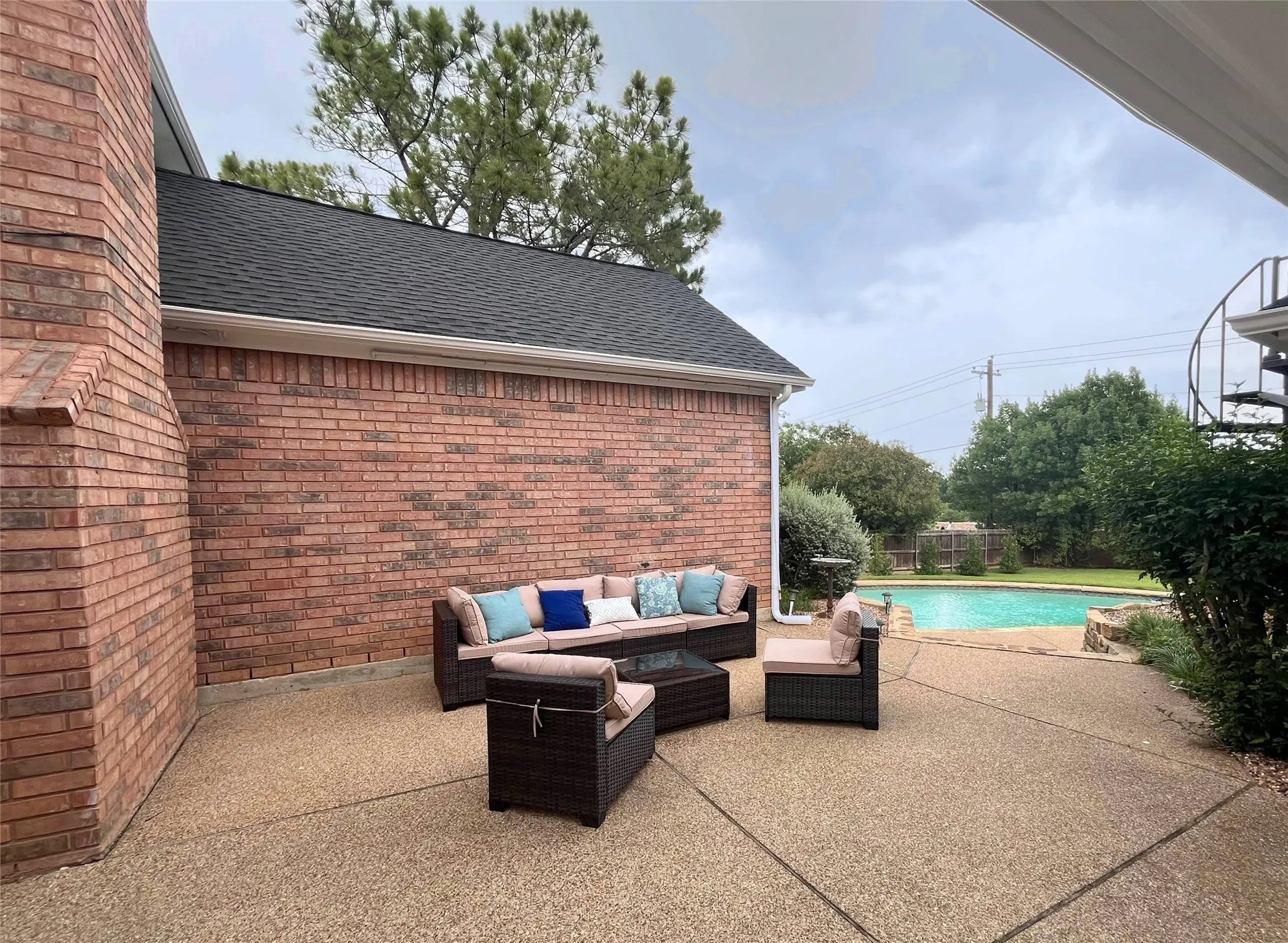 Beyond the patio dining area is an open patio for outdoor living that leads to the sparkling pool.