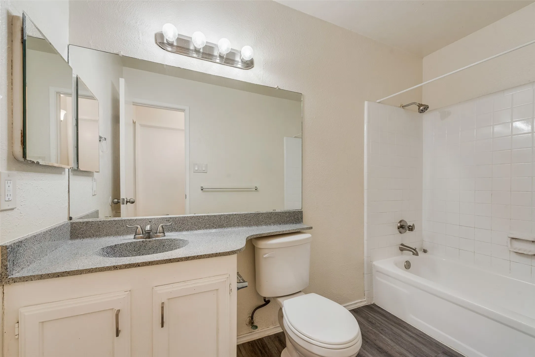 Bathroom vanity featuring a speckled countertop, undermount sink, and white cabinetry