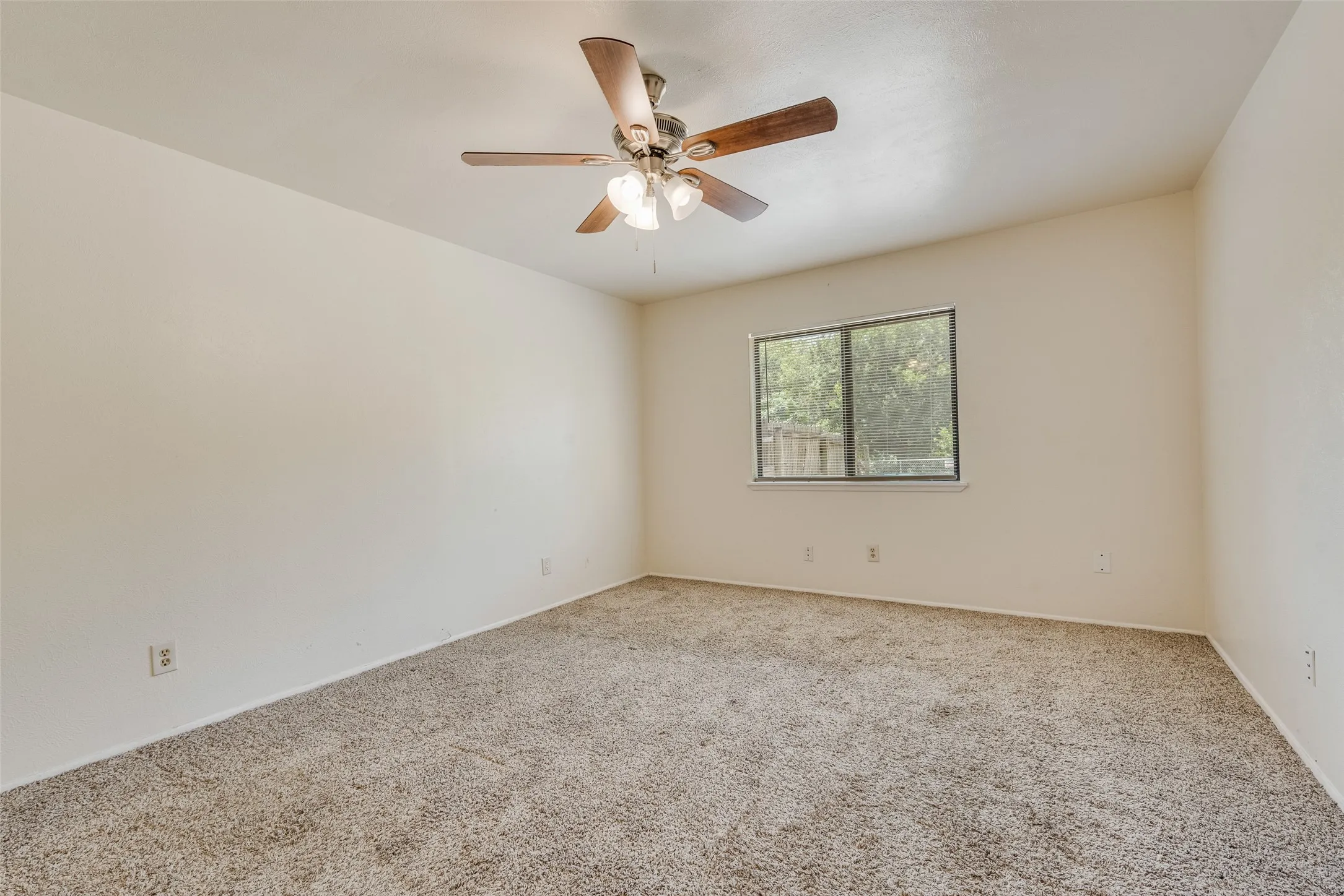 Carpeted room featuring a ceiling fan with integrated lighting, a single window, and light-toned walls