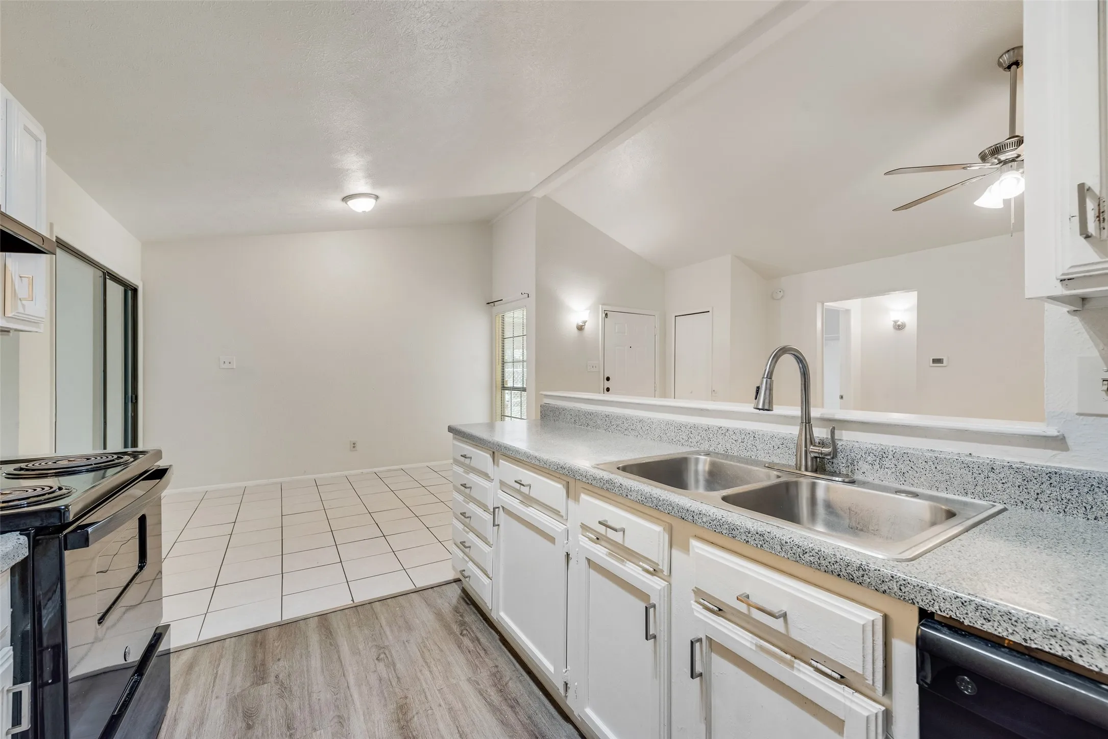 Kitchen featuring white cabinetry, a double basin stainless steel sink with gooseneck faucet, light grey speckled countertops, and wood-finish flooring