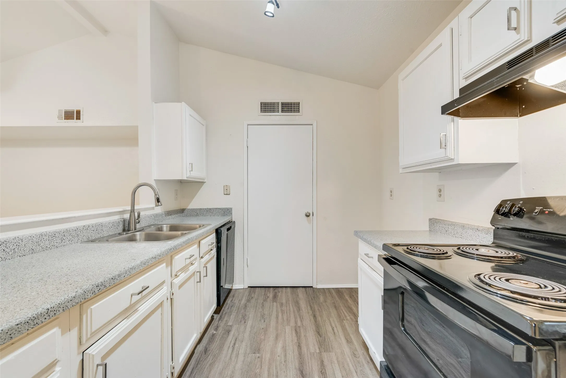 Kitchen featuring white cabinetry, light-toned countertops, a double basin stainless steel sink with a gooseneck faucet, black electric range with overhead ventilation, and wood-finish flooring