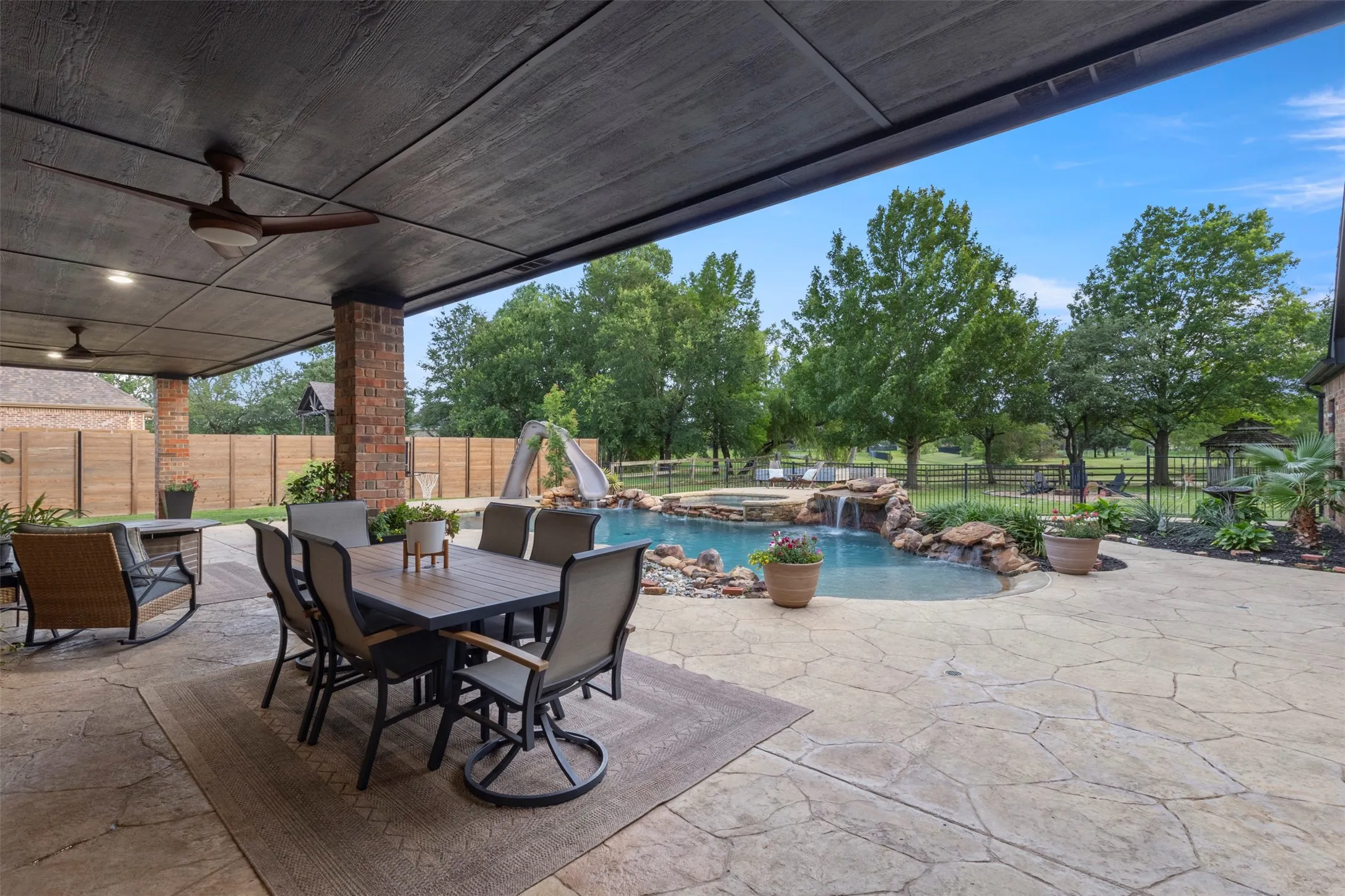Resort-style outdoor living with a spacious covered patio, expansive entertaining space, lush backyard views, and a sparkling pool converted to salt water—creating a private luxury retreat designed for relaxing and entertaining.
