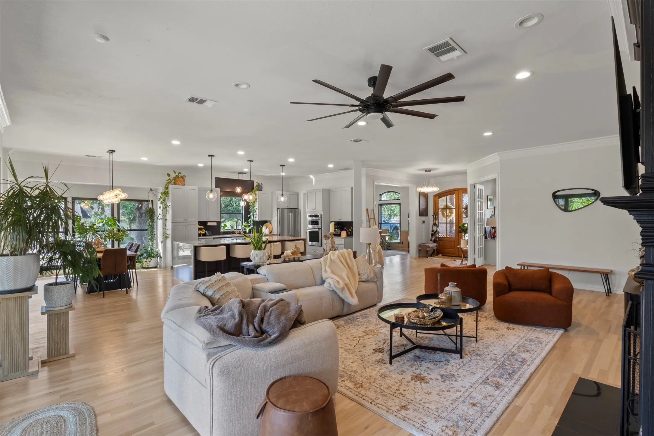 Expansive open-concept living area designed for luxury living, featuring white oak flooring, custom fireplace details, oversized sliding doors, and a seamless flow into the designer kitchen—perfect for elegant entertaining and everyday comfort.