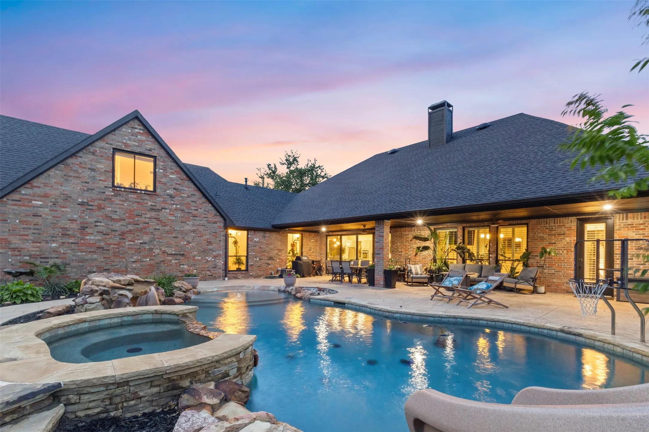 Stunning backyard retreat featuring a resort-style pool and spa, expansive covered patio, and warm ambient lighting — the perfect setting for relaxing evenings and entertaining
