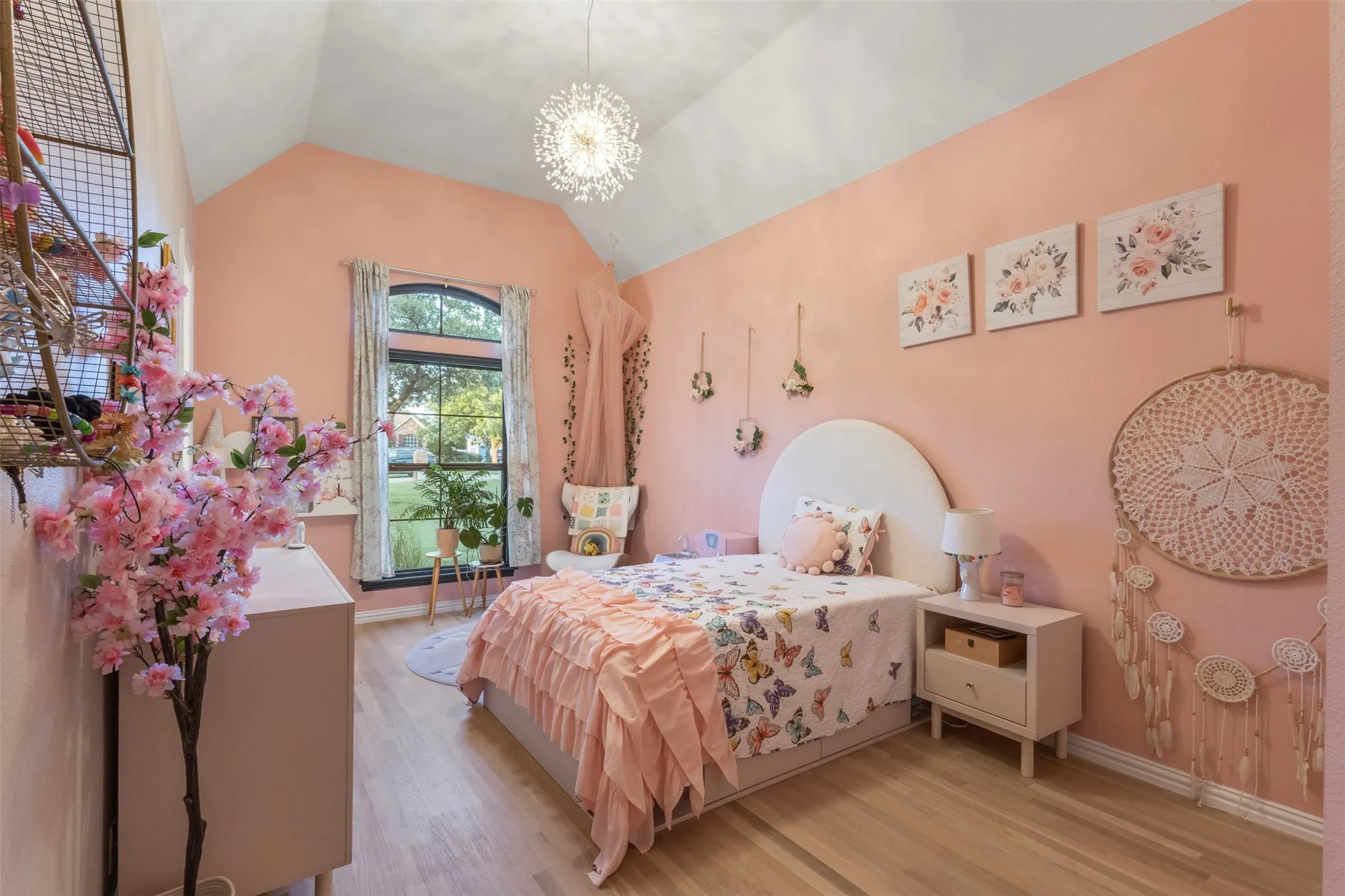 Charming secondary bedroom with vaulted ceilings, abundant natural light, updated trim details, and replaced white oak hardwood flooring—creating a bright, polished space with elevated designer appeal.