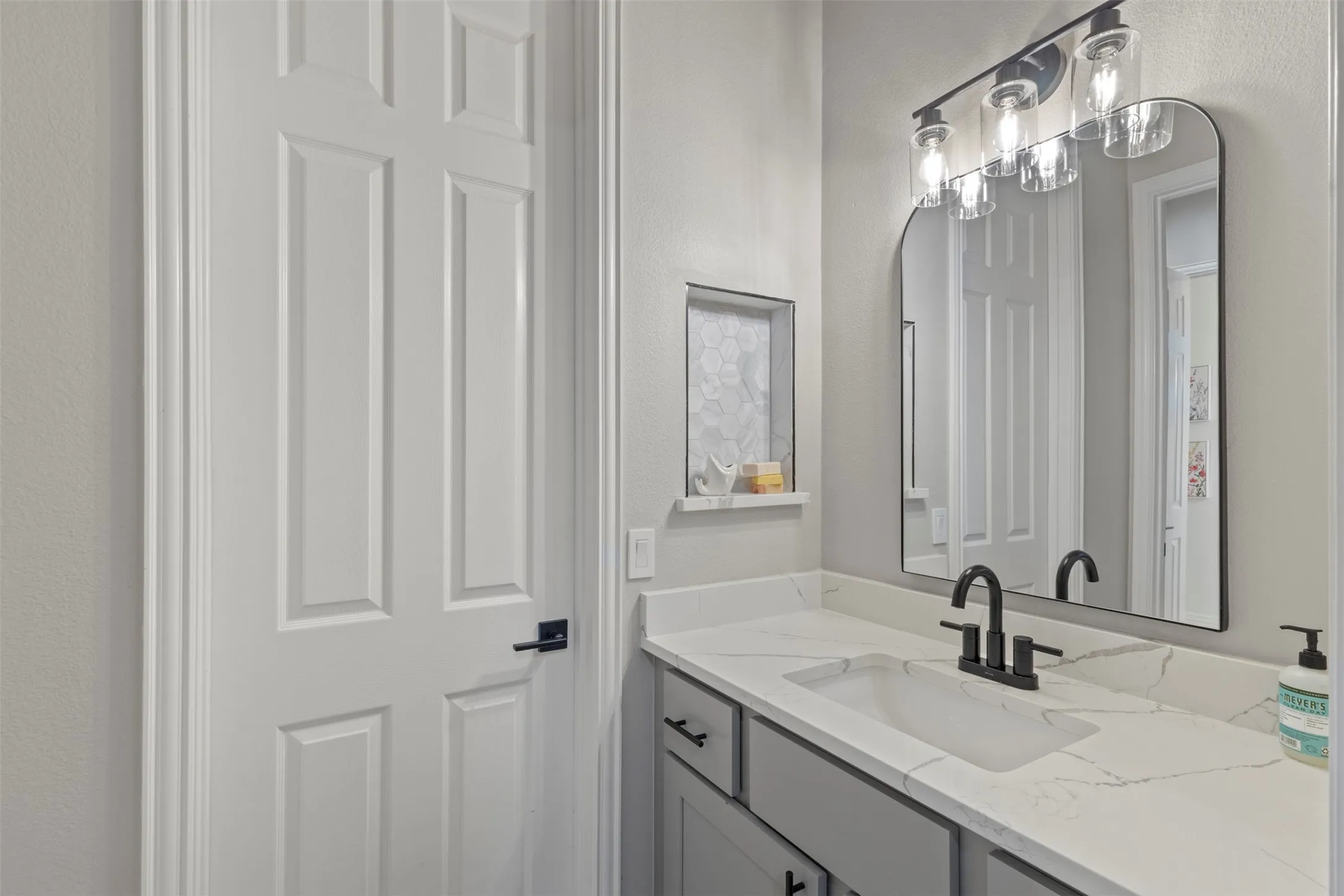 Fully renovated Jack-and-Jill bathroom featuring custom cabinetry, Calacatta quartz countertops, matte black hardware, new bathtub, and updated tile on the shower walls and flooring for a clean, elevated designer finish.