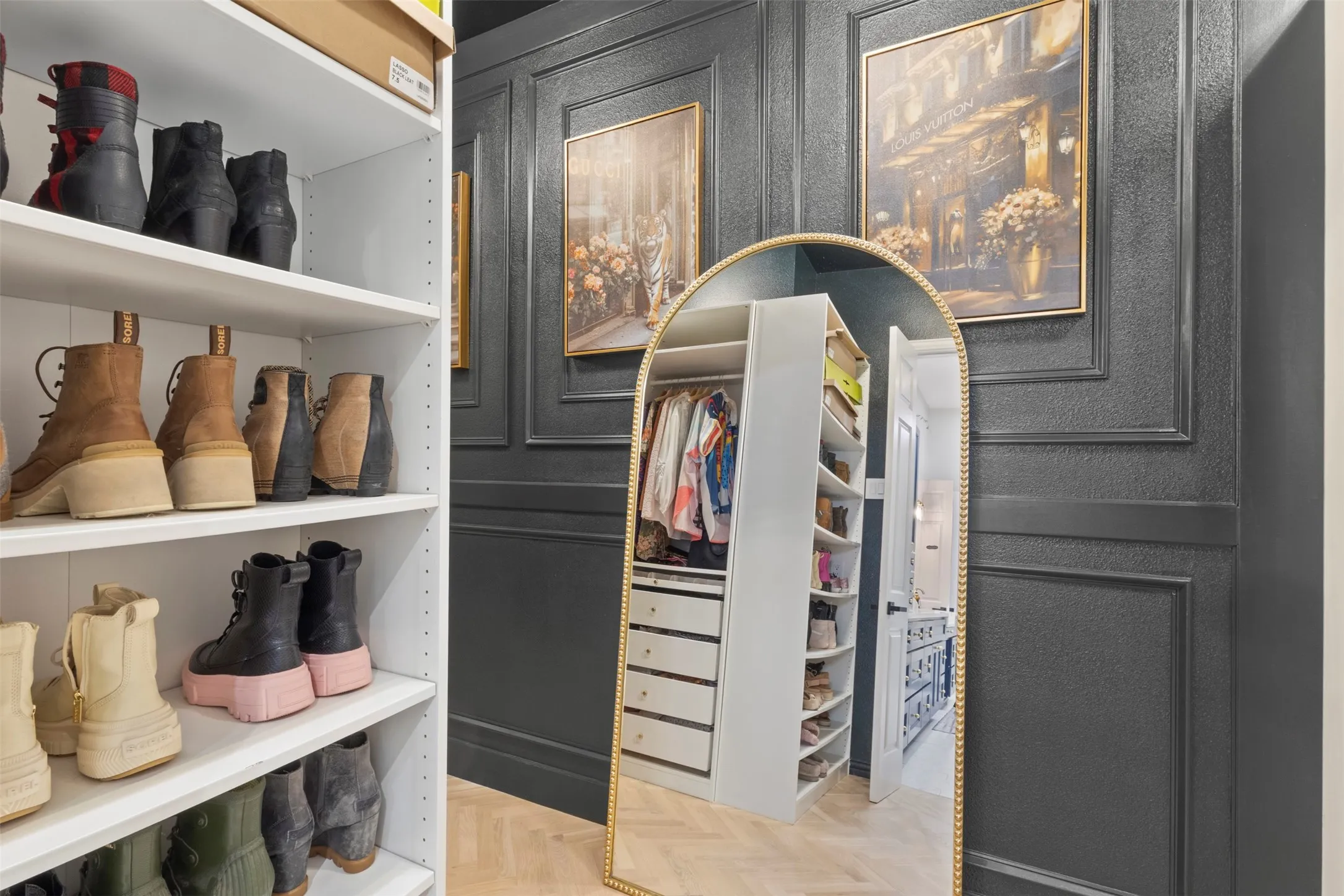 Luxury primary closet upgraded with custom cabinetry and shelving, herringbone white oak hardwood floors, new lighting, and a dramatic Sherwin-Williams Nocturnal Green accent wall—creating a boutique-style dressing space with designer appeal.