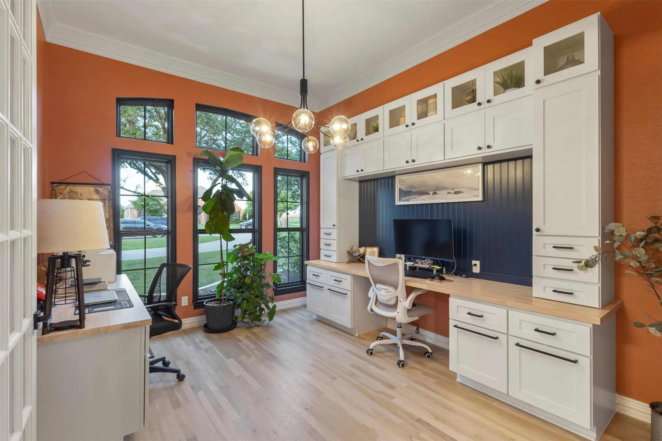 Designer office with expansive custom built-ins, dual wall towers, four filing drawers, upper glass display cabinetry, and a butcher block countertop stain-matched to the white oak flooring—creating a polished, functional workspace with luxury-level detail.