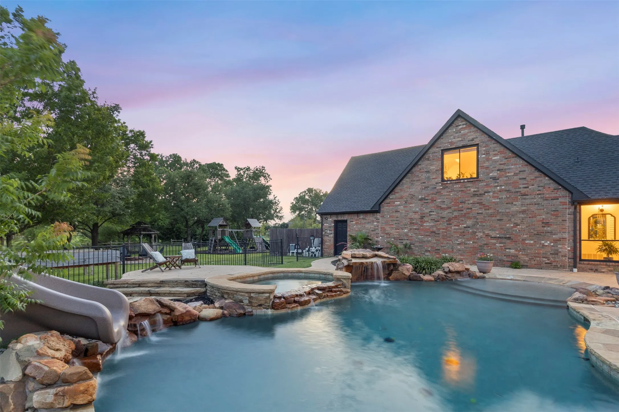 Resort-style backyard featuring a saltwater pool with updated heater, pumps, and waterfall motor, plus a rock waterfall, spa, and slide—creating a private outdoor retreat designed for luxury entertaining and relaxation.
