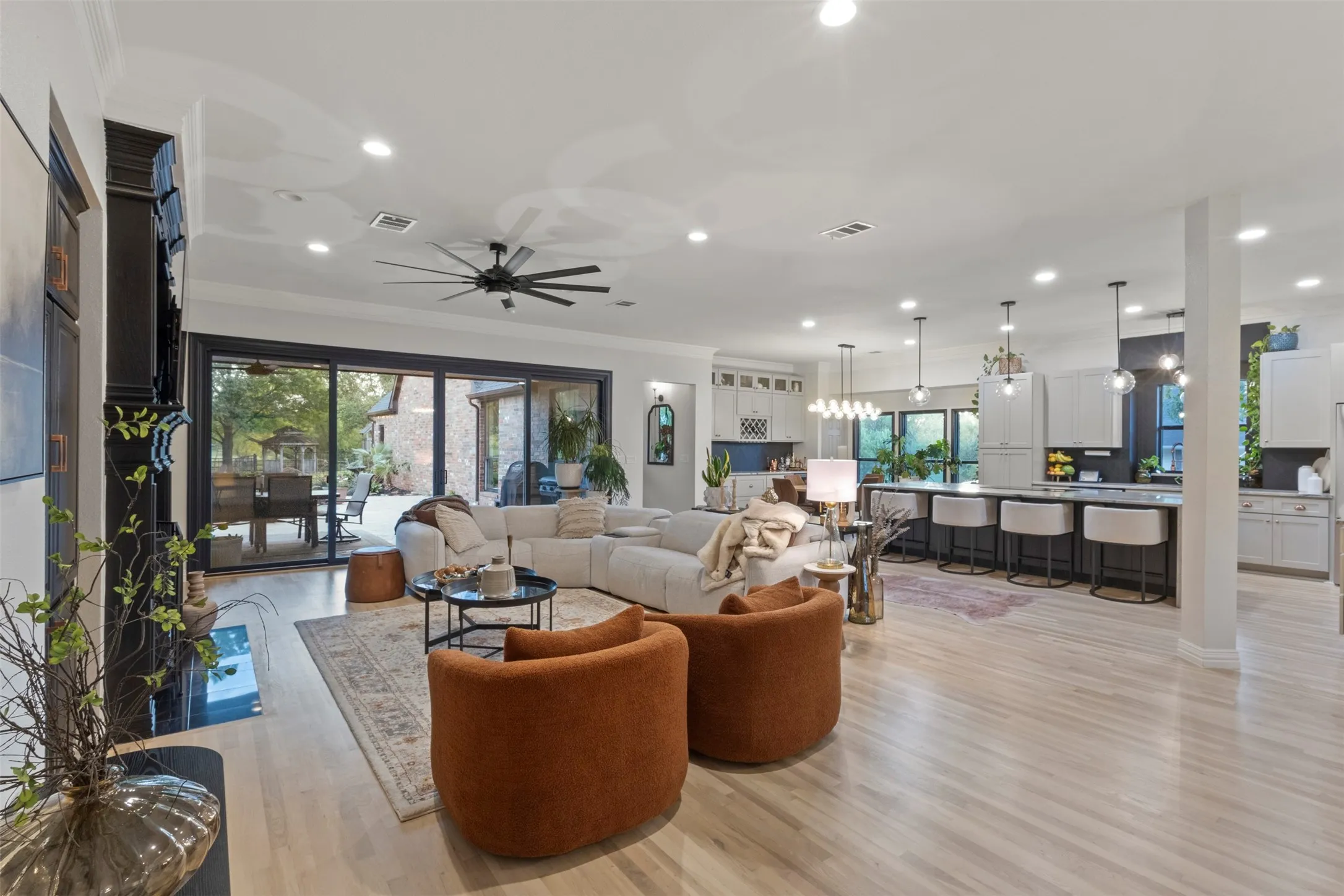 Expansive open-concept living area designed for luxury living, featuring white oak flooring, custom fireplace details, oversized sliding doors, and a seamless flow into the designer kitchen—perfect for elegant entertaining and everyday comfort.
