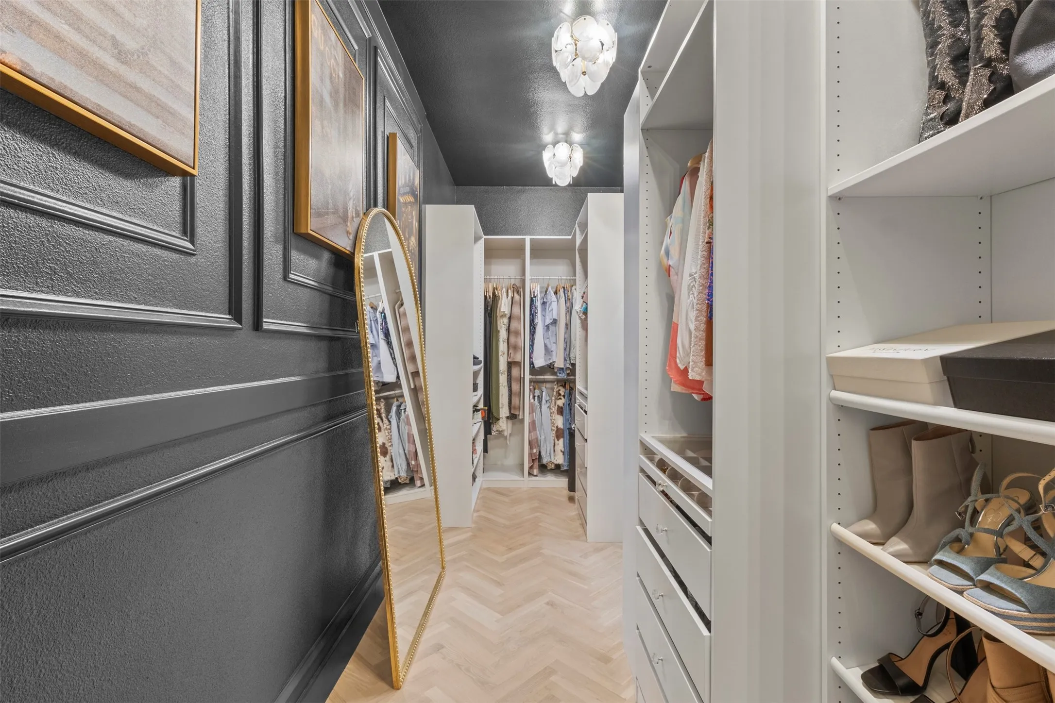 Luxury primary closet upgraded with custom cabinetry and shelving, herringbone white oak hardwood floors, new lighting, and a dramatic Sherwin-Williams Nocturnal Green accent wall—creating a boutique-style dressing space with designer appeal.