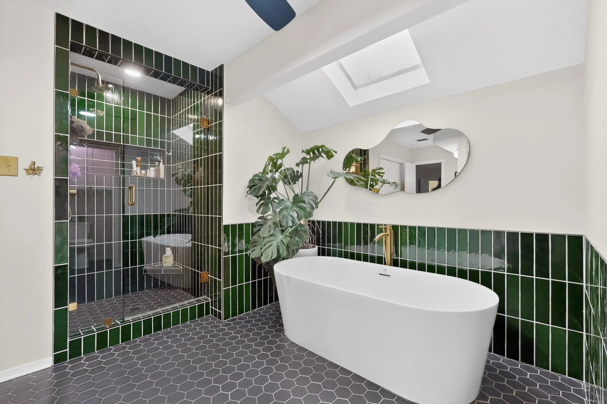Contemporary bathroom featuring a freestanding soaking tub, a frameless glass shower enclosure, and dark green subway tile accents