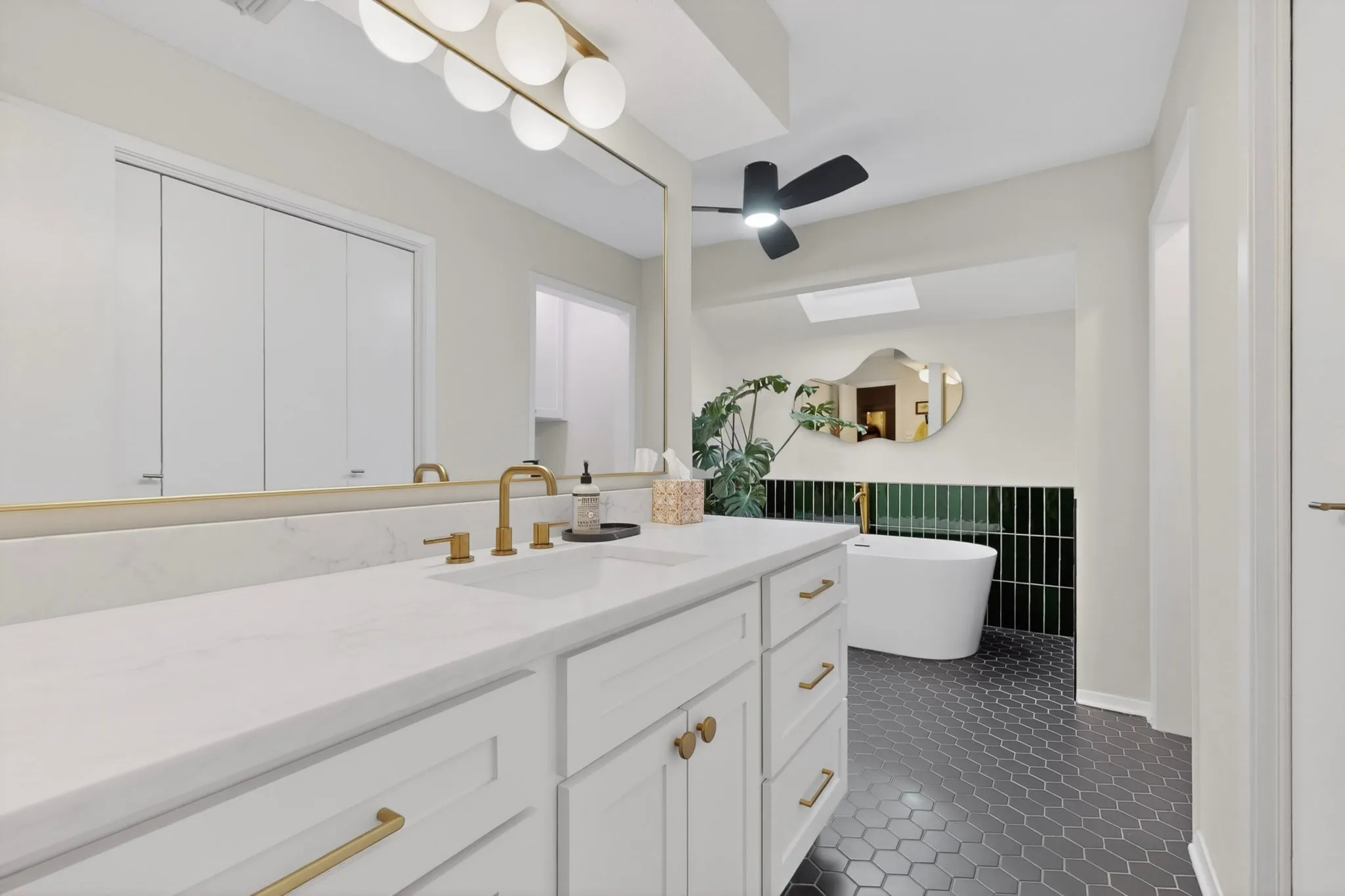 Bathroom featuring a white vanity with gold hardware, a white countertop, and gold-finish fixtures