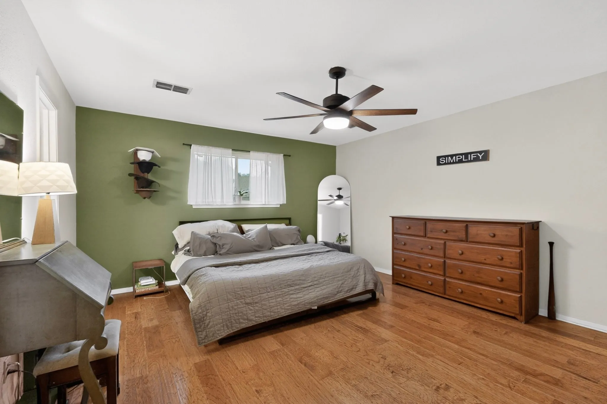 Bedroom featuring wood-finish flooring, a ceiling fan with integrated lighting, and a window with sheers