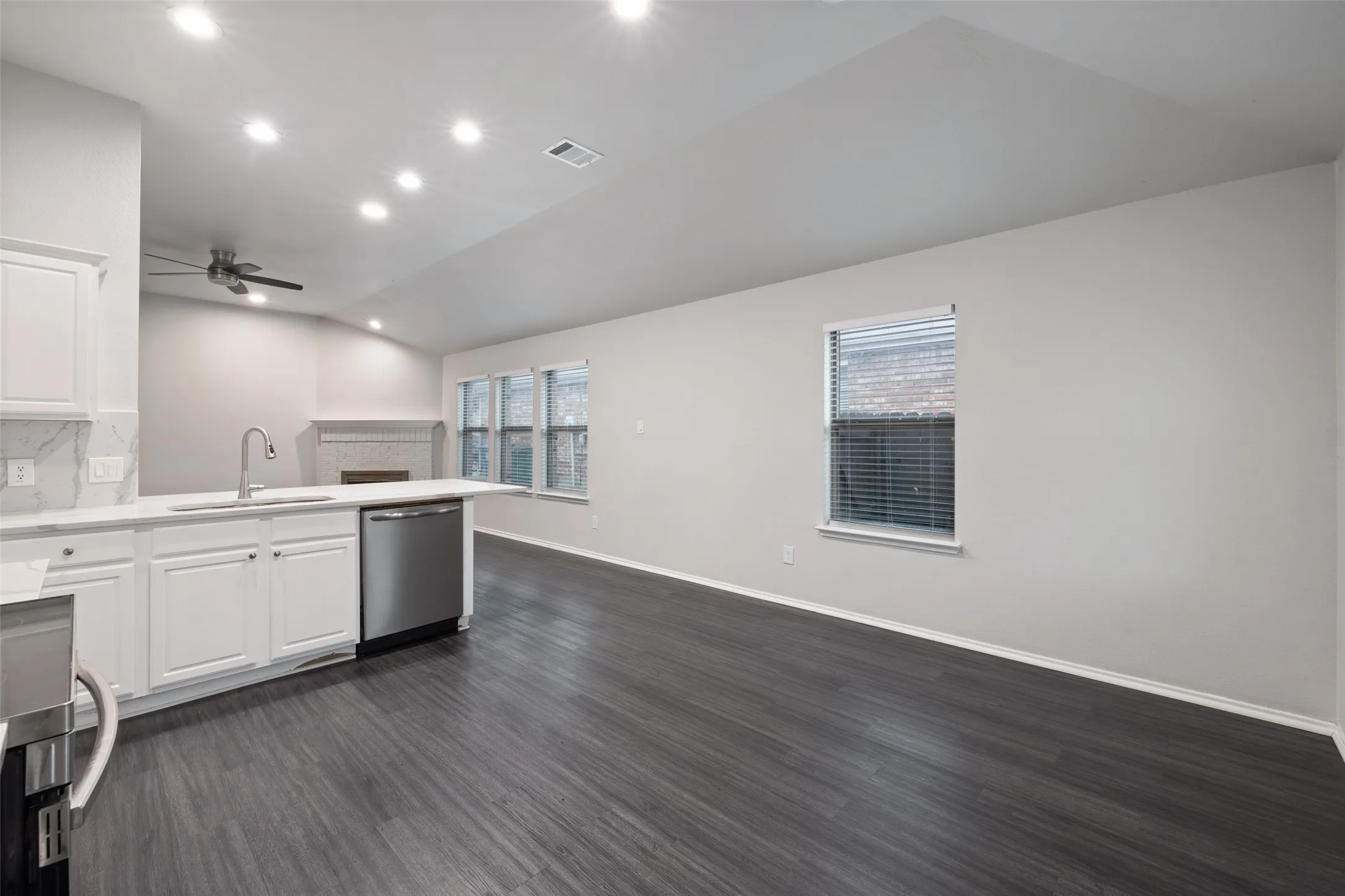 Kitchen featuring dark hardwood / wood-style flooring, stainless steel dishwasher, white cabinets, tasteful backsplash, and ceiling fan