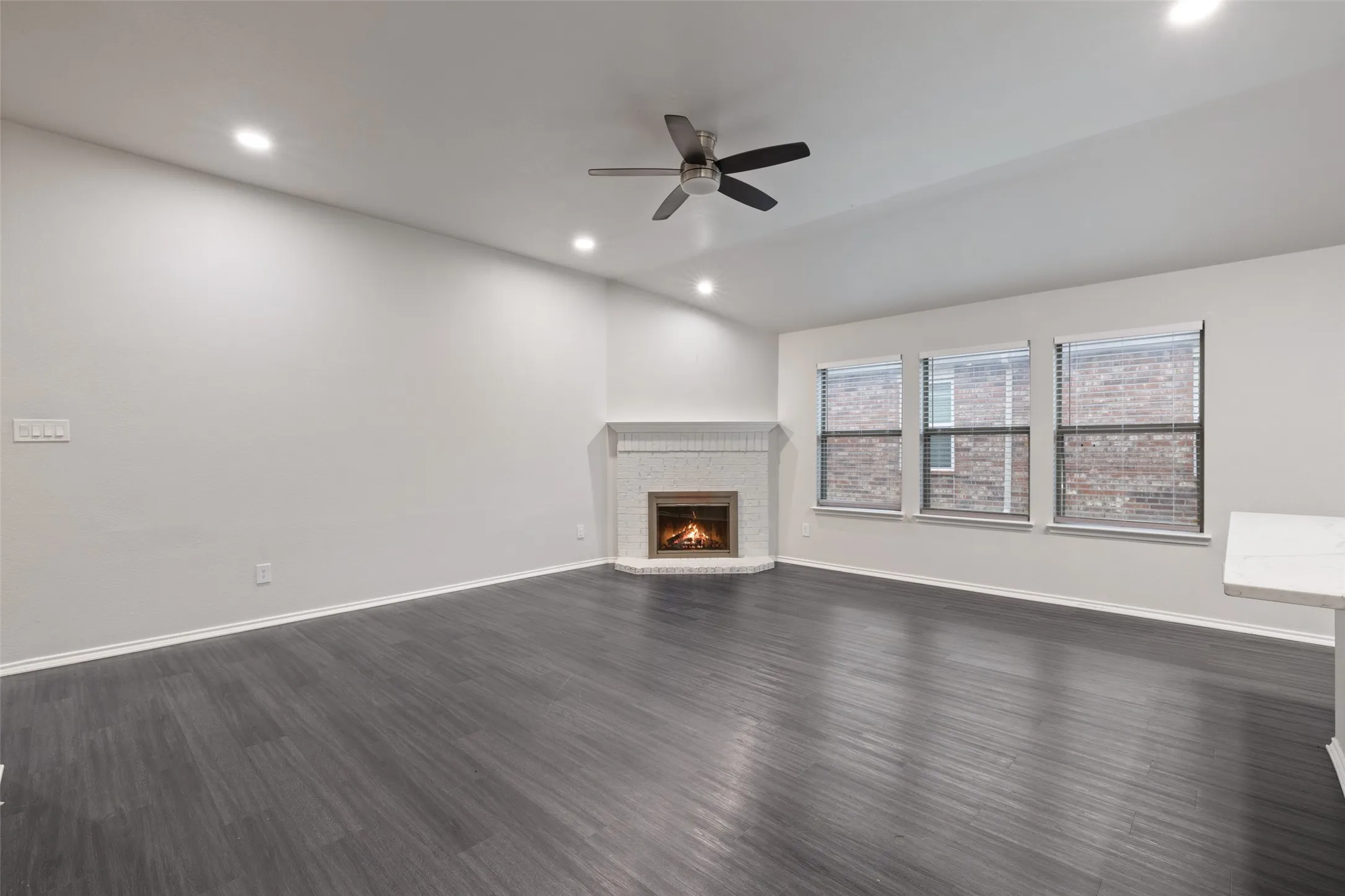Unfurnished living room with lofted ceiling, ceiling fan, dark hardwood / wood-style floors, and a fireplace