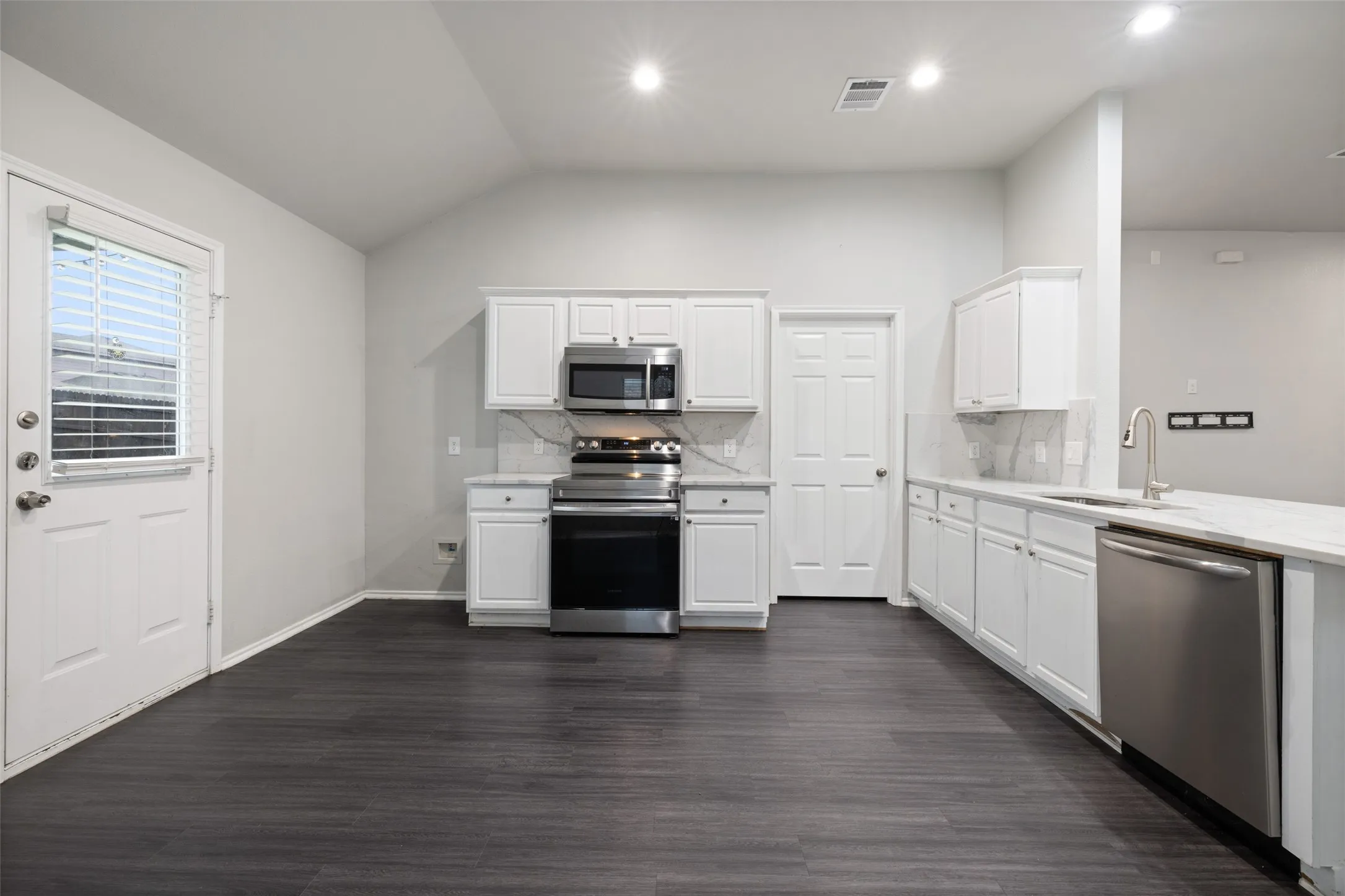 Kitchen with appliances with stainless steel finishes, dark hardwood / wood-style flooring, sink, and tasteful backsplash