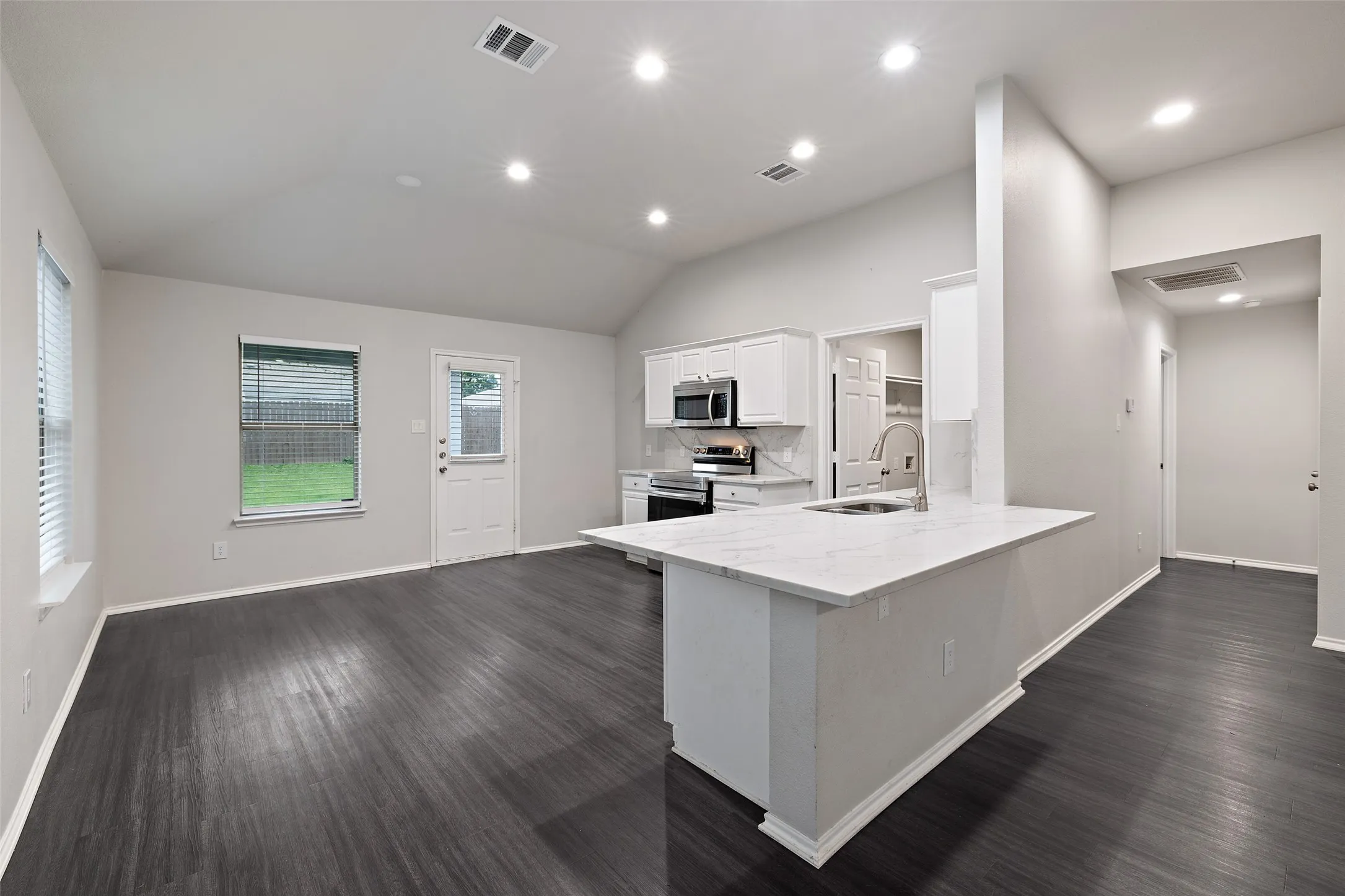 Kitchen with dark hardwood / wood-style floors, stainless steel appliances, backsplash, white cabinets, and sink