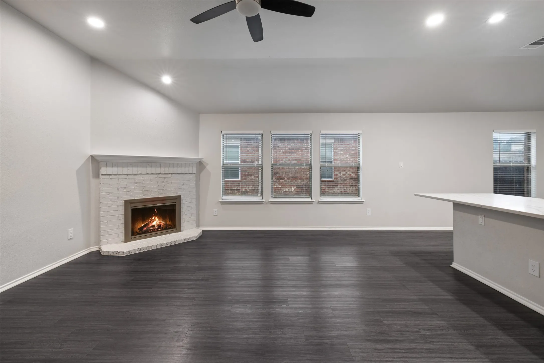 Unfurnished living room featuring vaulted ceiling, ceiling fan, dark hardwood / wood-style floors, and a fireplace