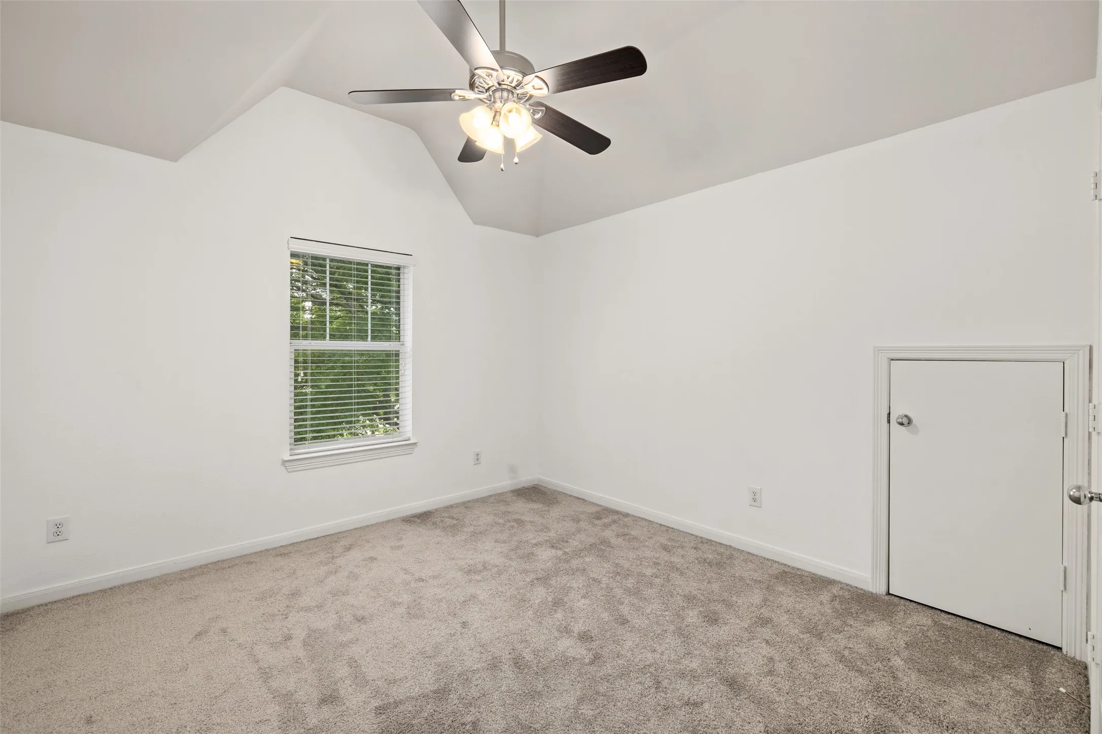 Empty room featuring lofted ceiling, ceiling fan, and carpet floors
