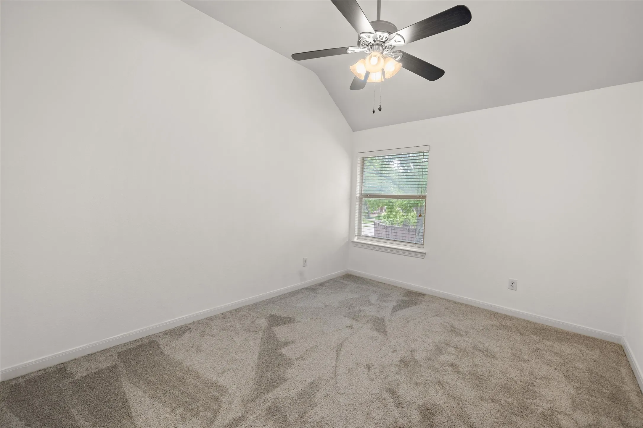 Unfurnished room featuring carpet flooring, ceiling fan, and vaulted ceiling