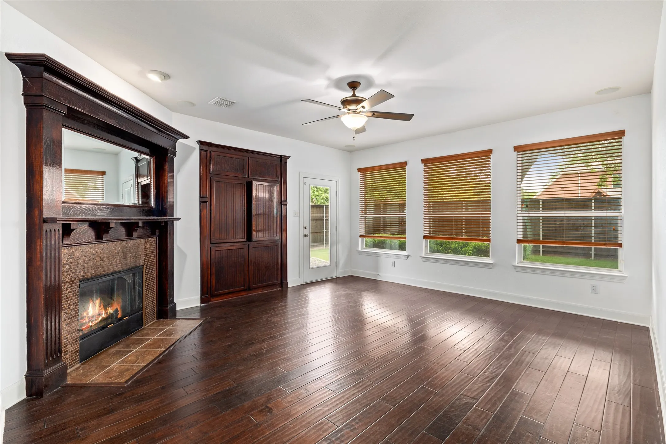 Unfurnished living room with ceiling fan, a fireplace, and dark hardwood / wood-style flooring