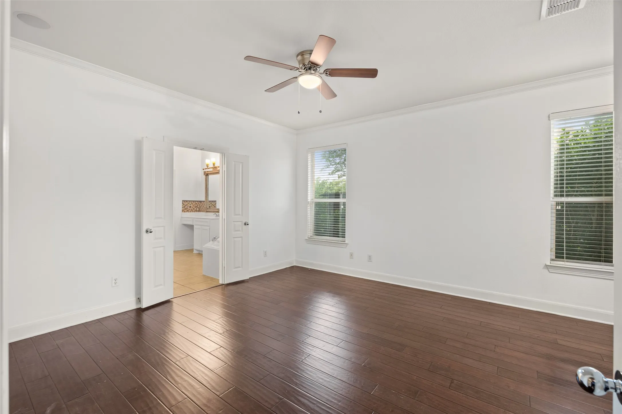 Featuring ensuite bath, ceiling fan, crown molding, and dark hardwood / wood-style flooring