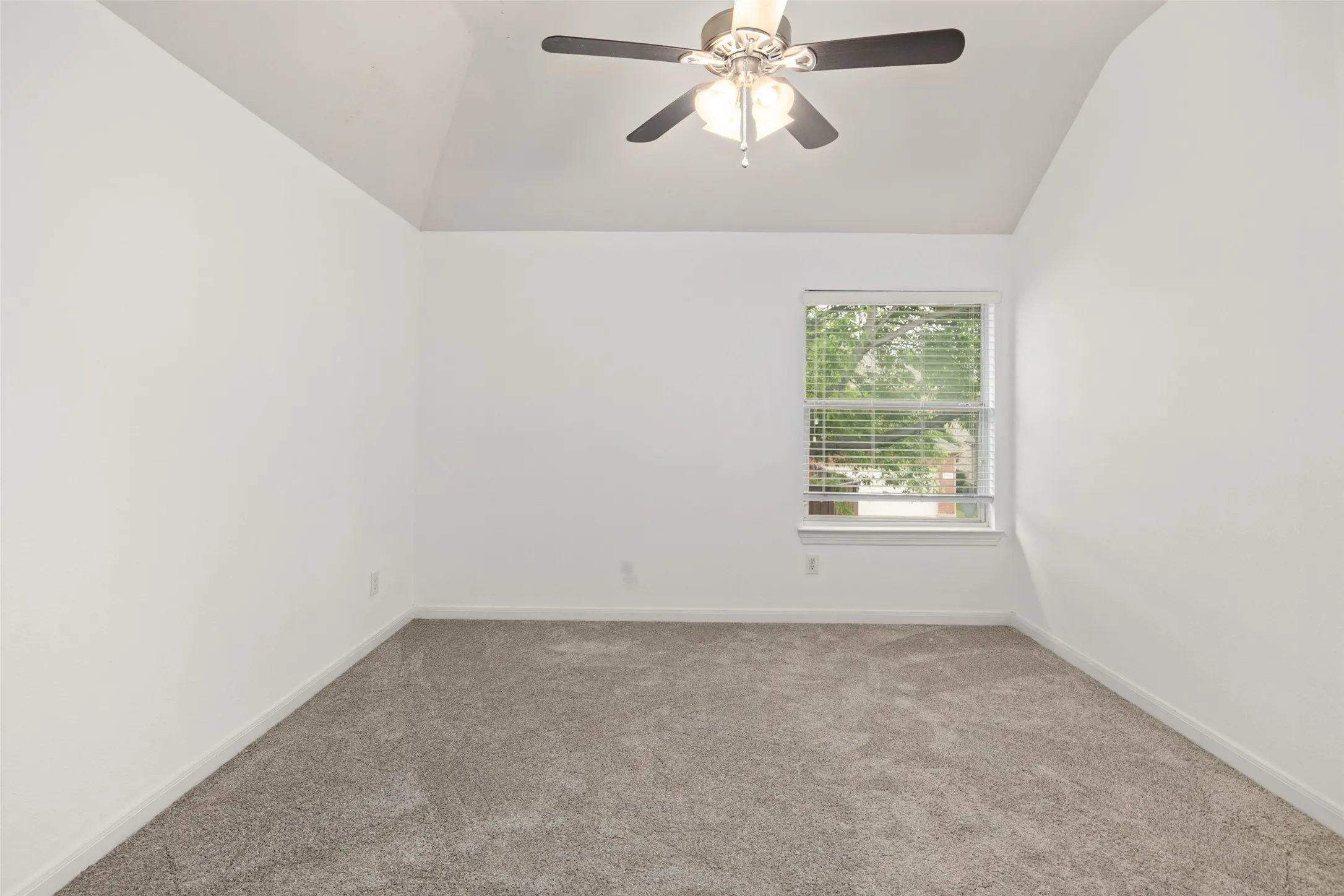 Carpeted empty room with lofted ceiling and ceiling fan