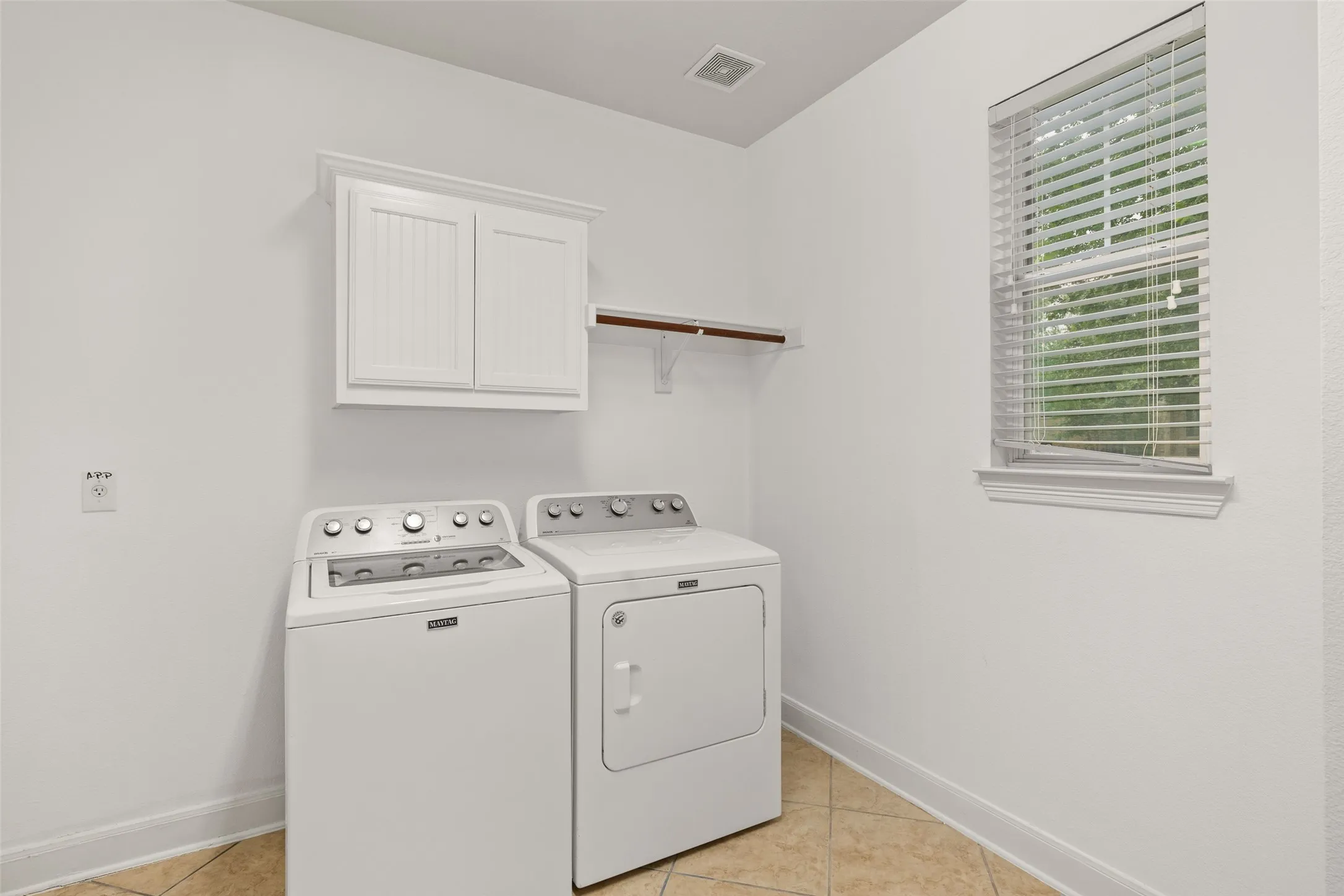 Washroom with washer and clothes dryer, cabinets, and light tile floors