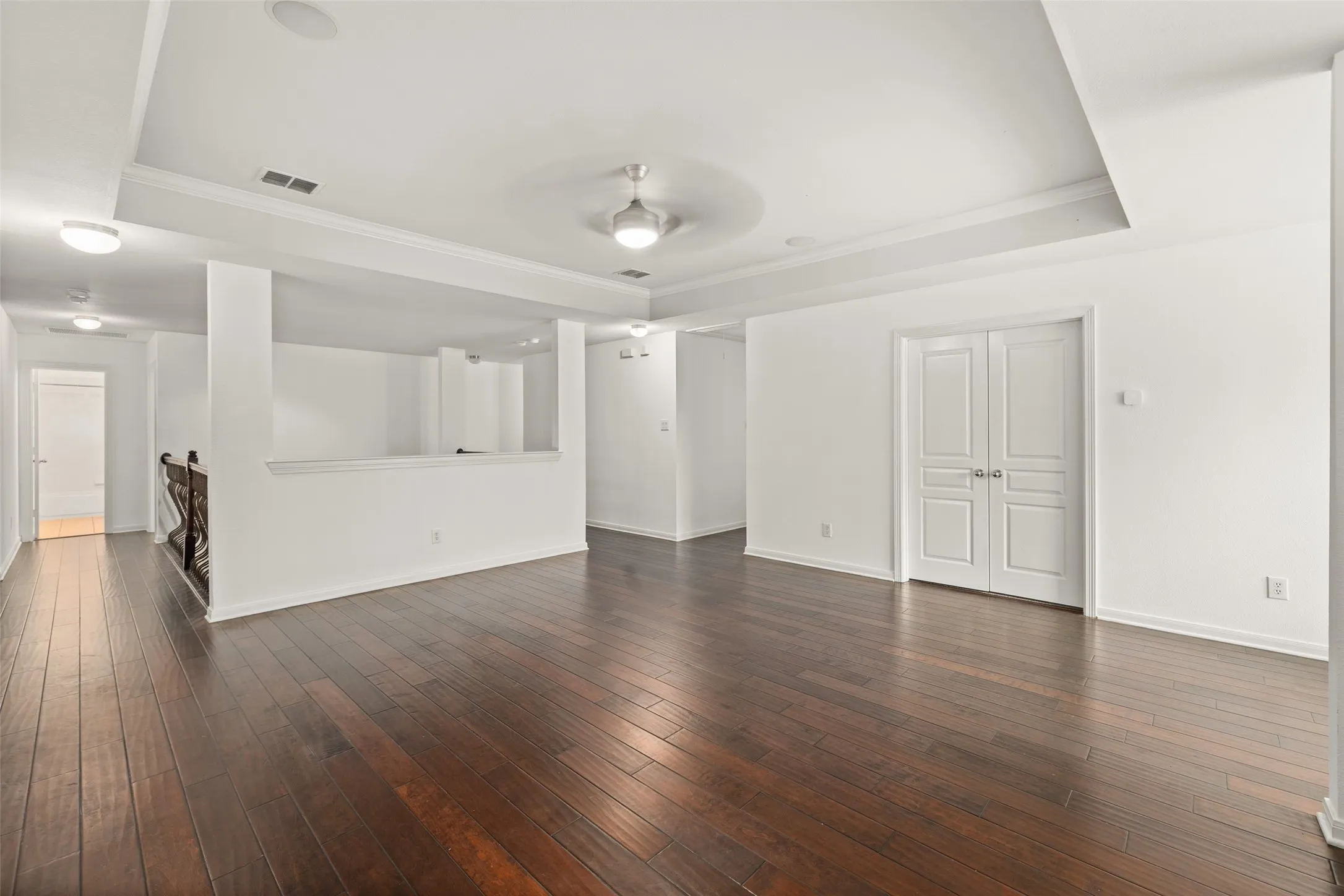 Living room with ceiling fan, a tray ceiling, and dark hardwood / wood-style floors