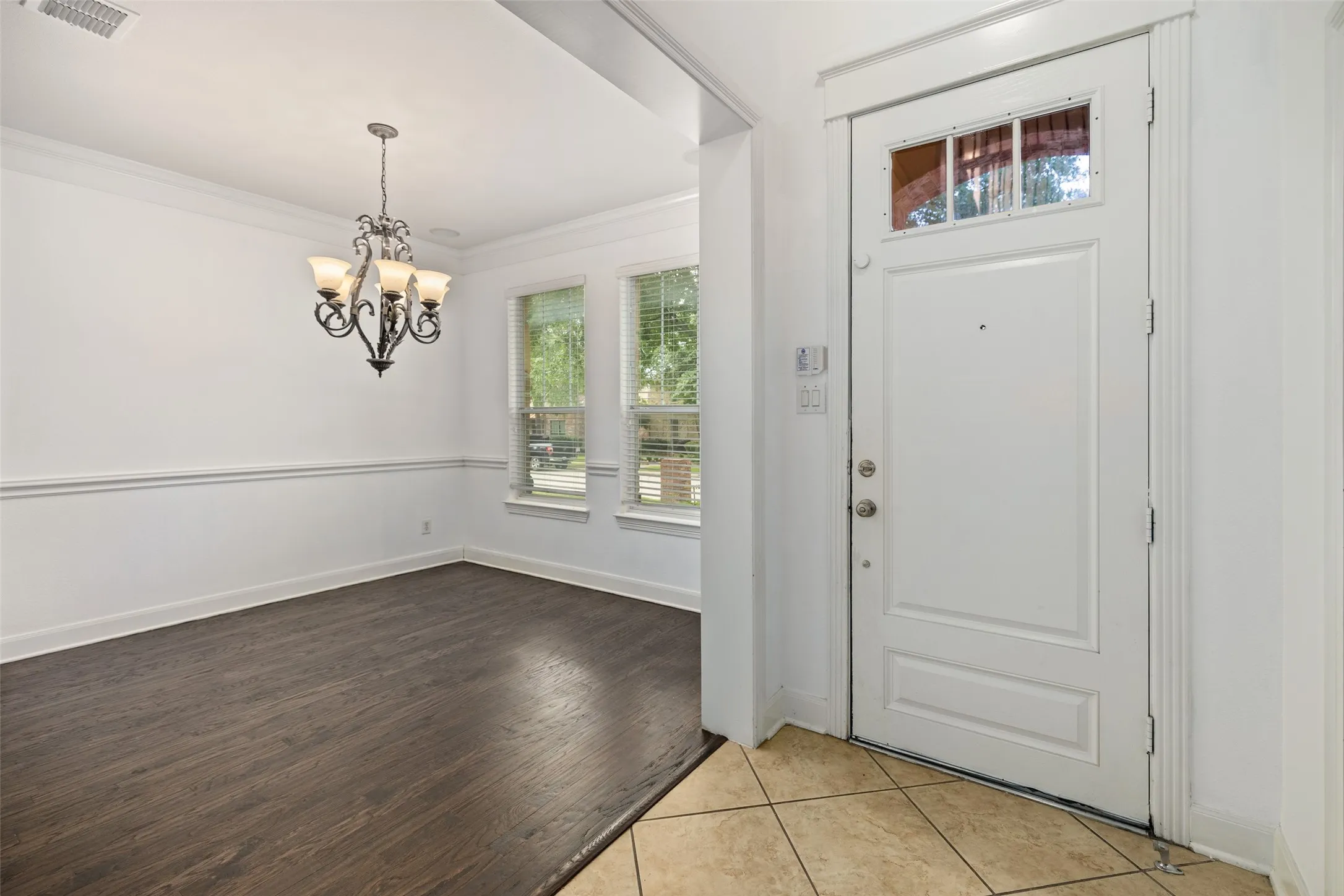 Foyer with a chandelier, crown molding, and light tile flooring
