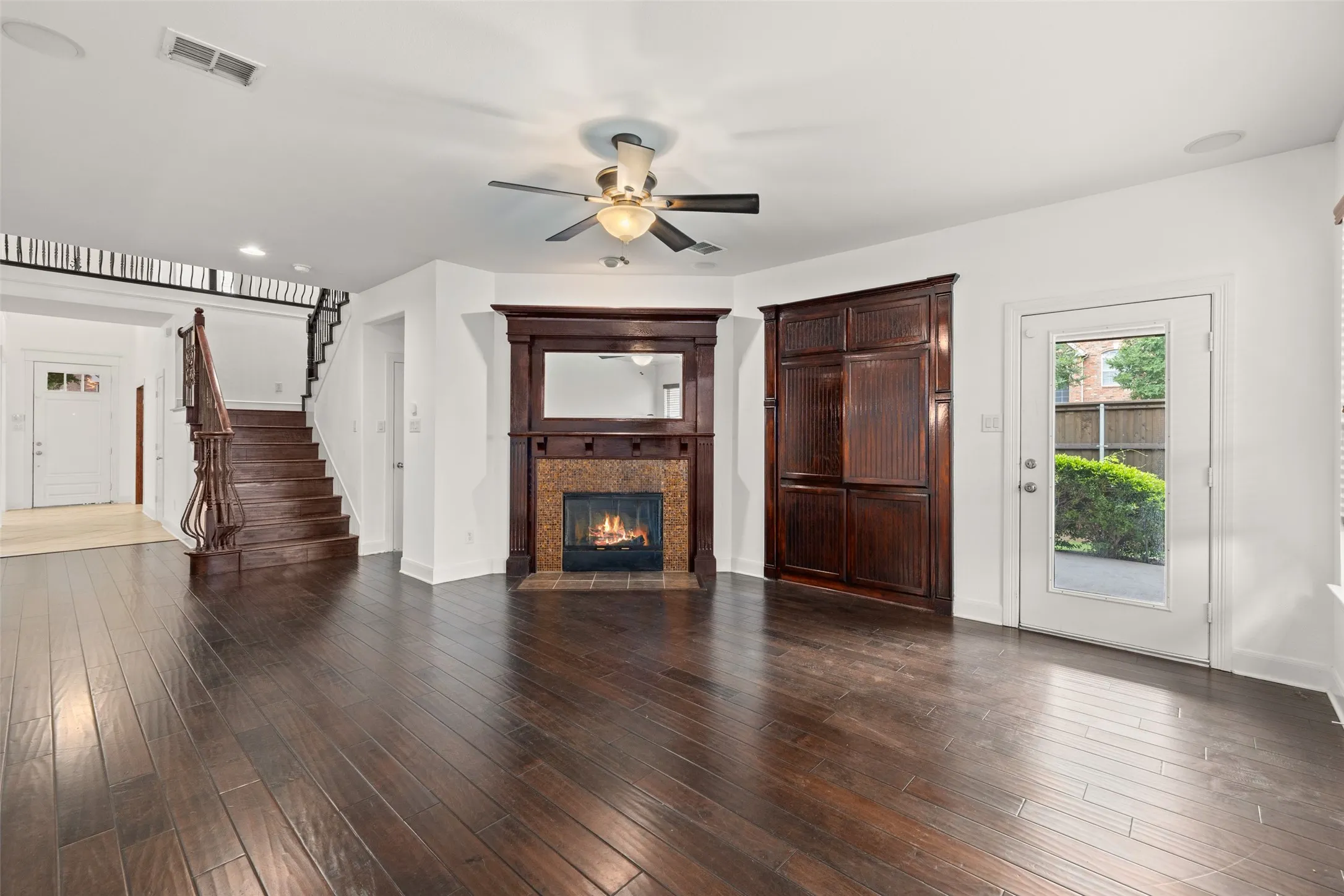 Unfurnished living room featuring ceiling fan, a tile fireplace, and dark hardwood / wood-style floors