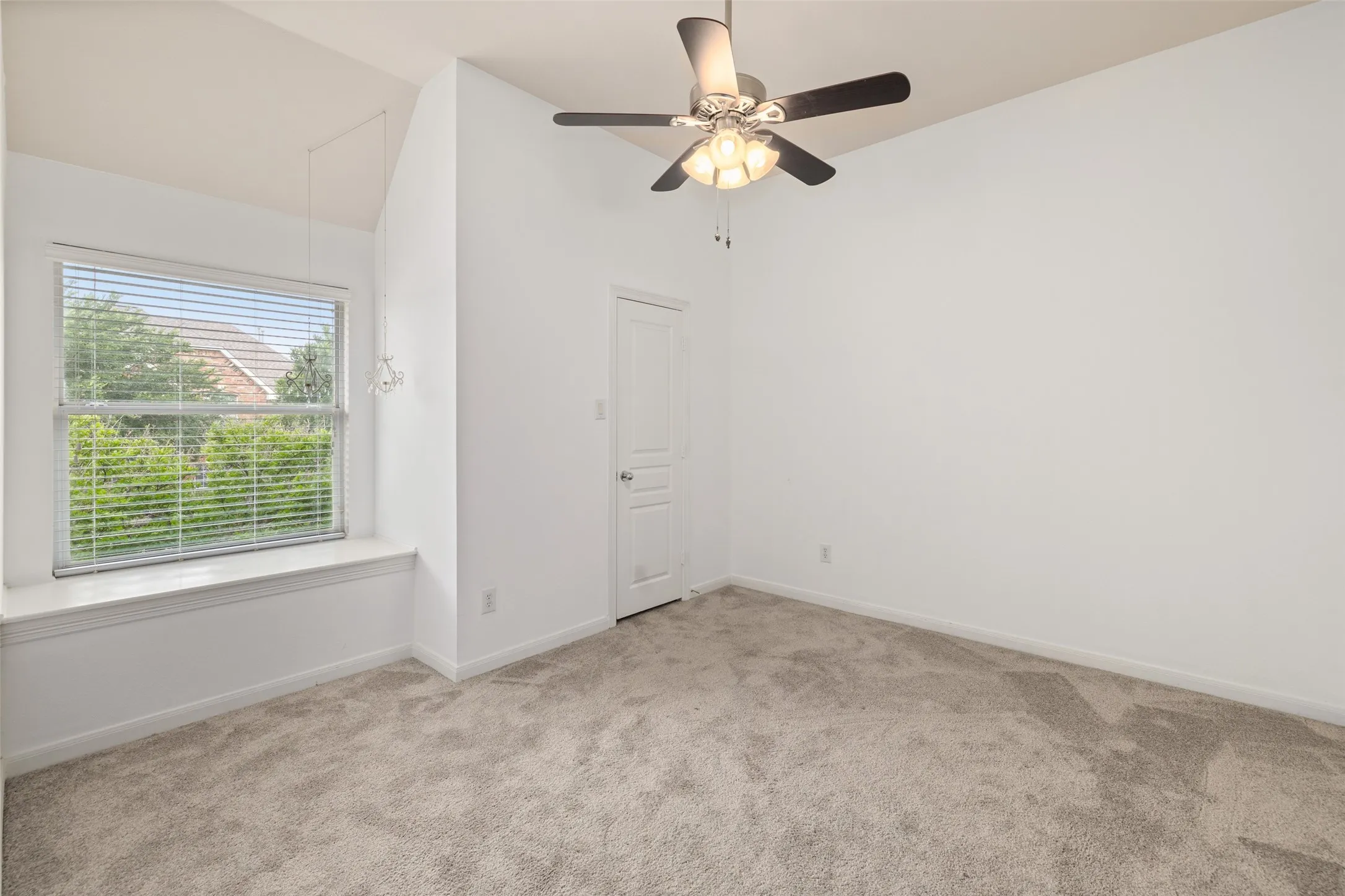 Carpeted empty room with ceiling fan and lofted ceiling