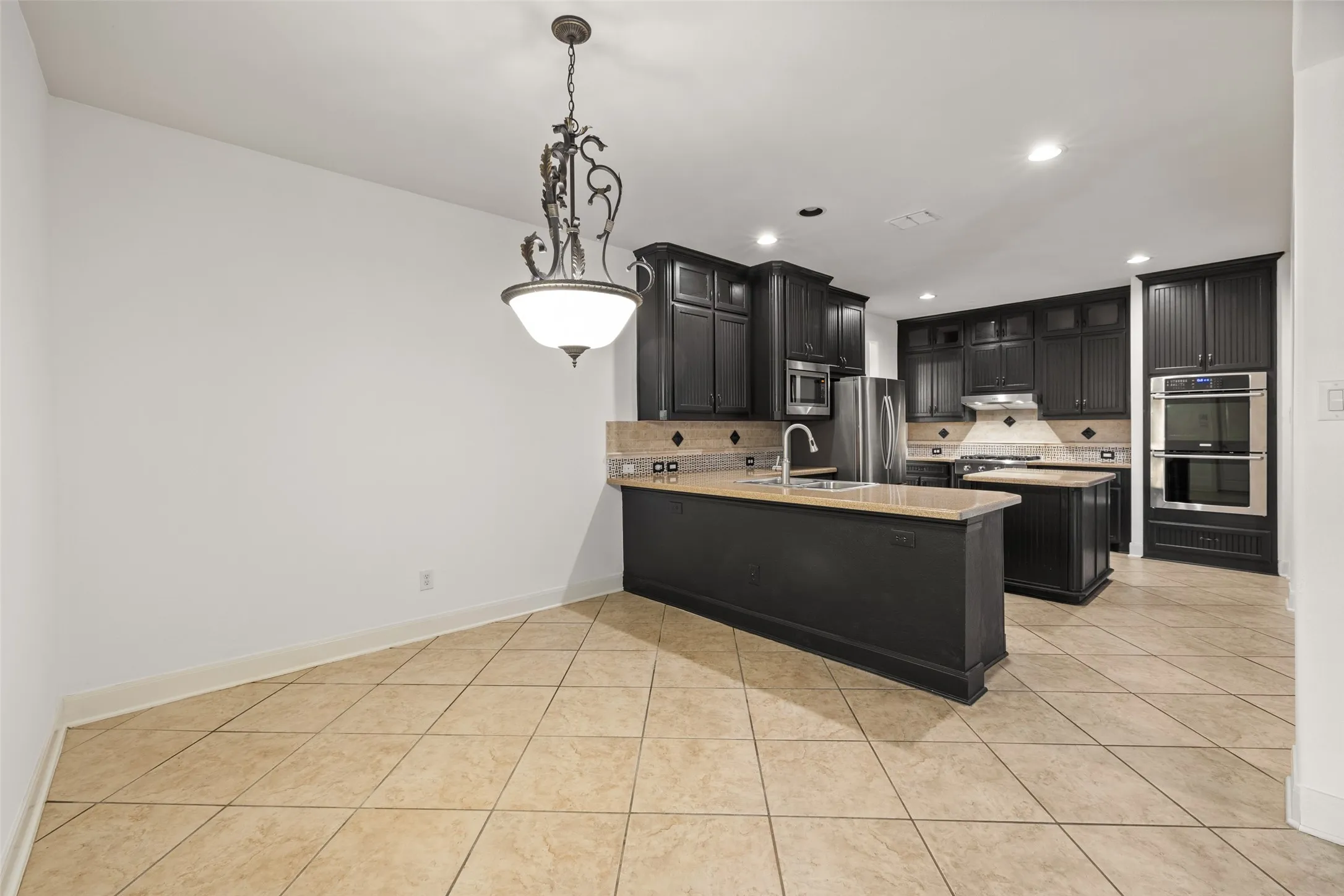 Kitchen with sink, tasteful backsplash, hanging light fixtures, stainless steel appliances, and kitchen peninsula