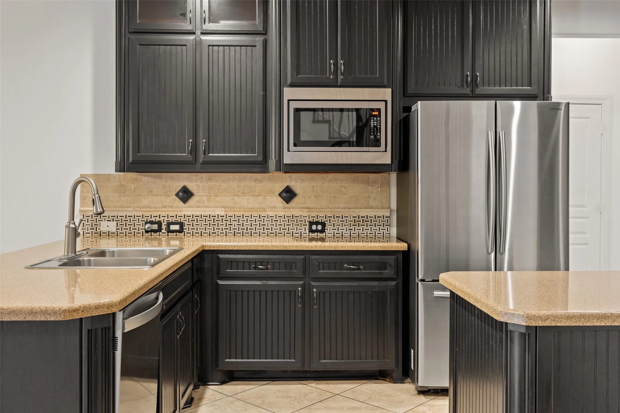 Kitchen with light tile floors, sink, tasteful backsplash, stainless steel appliances, and kitchen peninsula