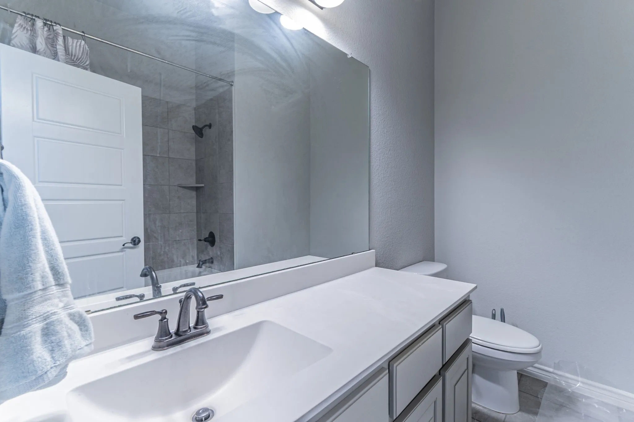 Bathroom vanity with a white rectangular undermount sink, brushed nickel faucet, and a light-toned countertop