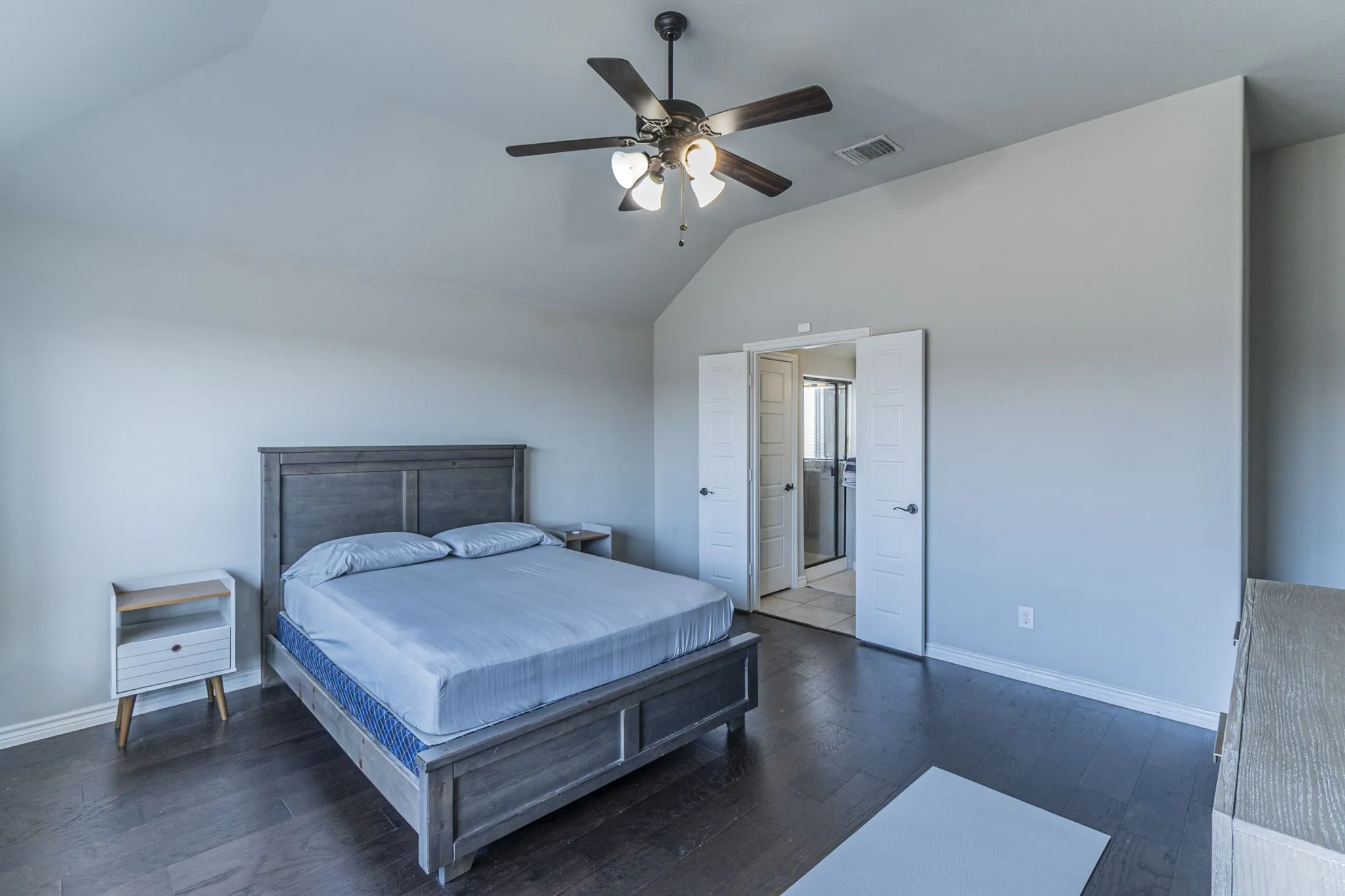 Spacious room with vaulted ceilings and dark wood-finish flooring