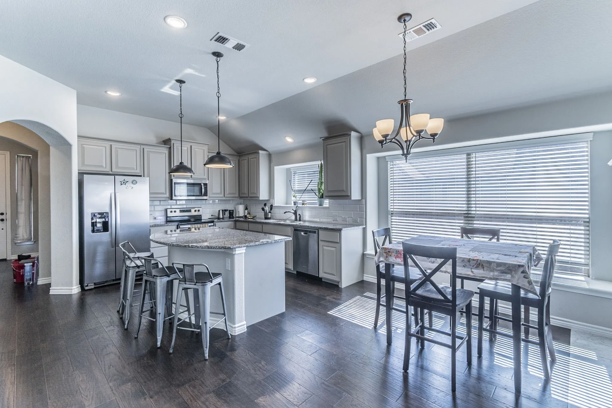 Spacious kitchen featuring gray cabinetry, stainless steel appliances, and a central island with a granite countertop