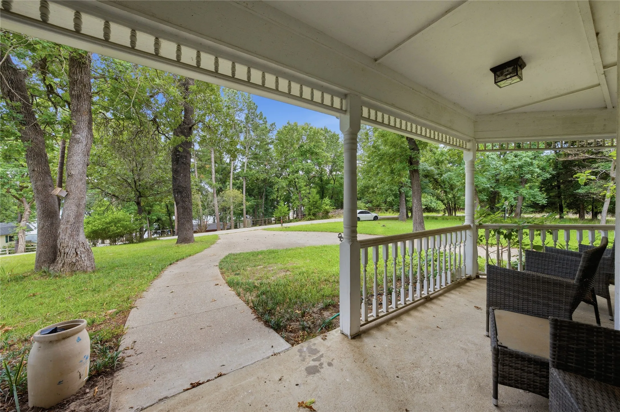 Covered front porch featuring white balusters and a decorative ceiling trim