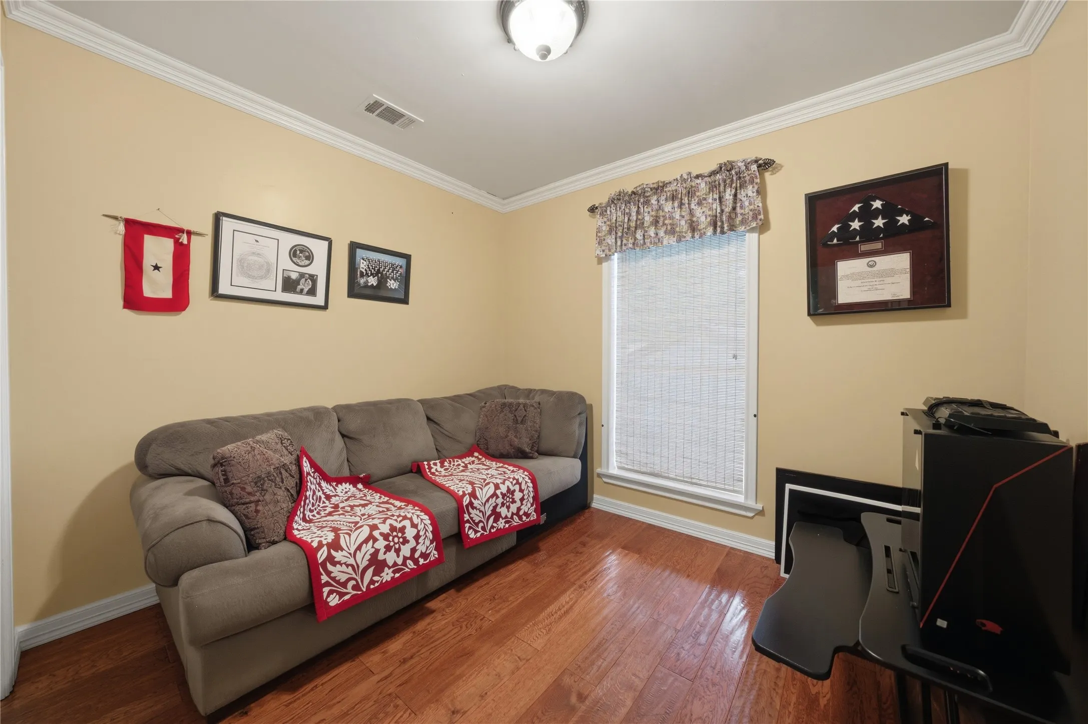 Versatile interior space featuring wood-finish flooring, light-colored walls, and classic crown molding