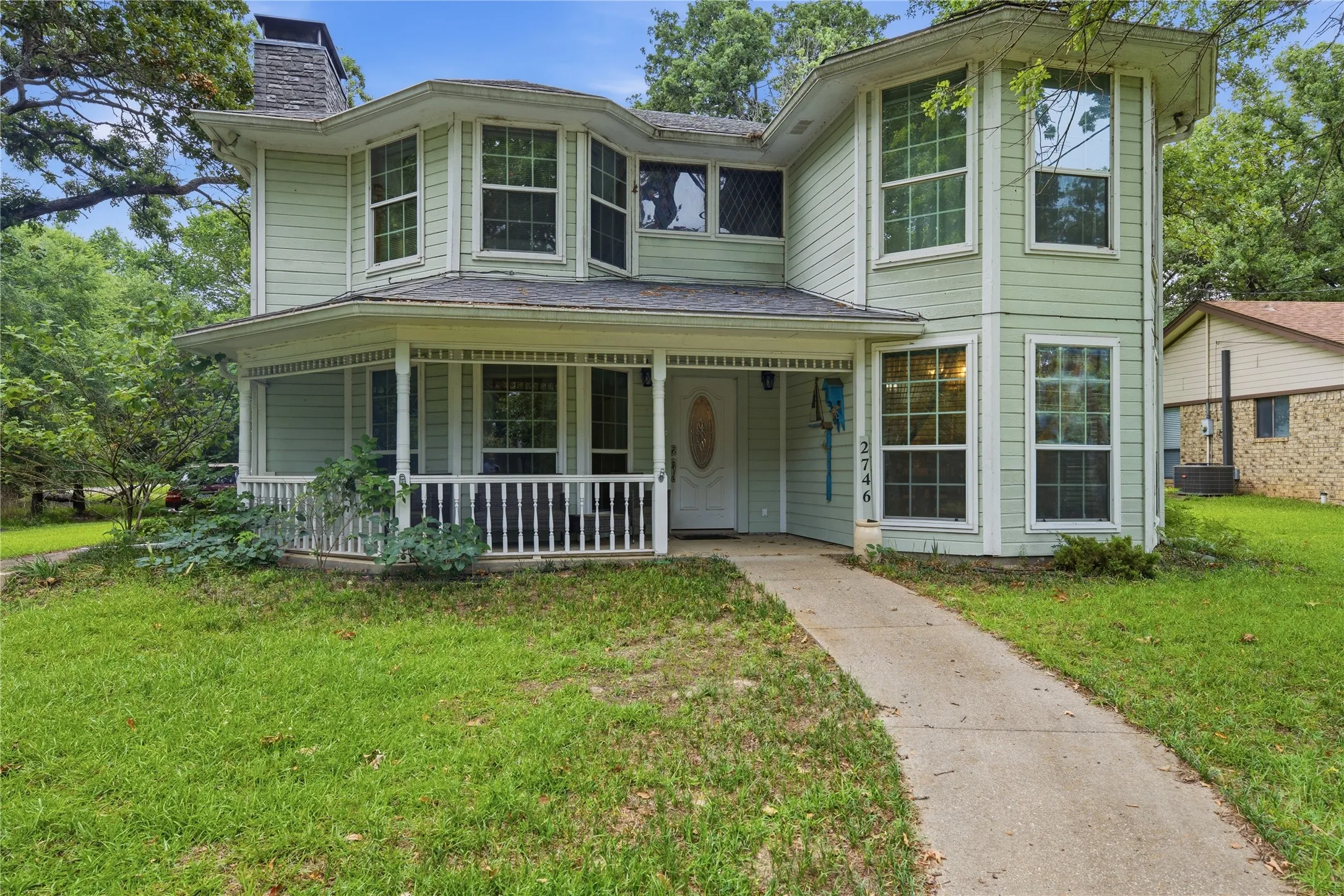 Two-story residence featuring light green siding and a covered front porch with white railings
