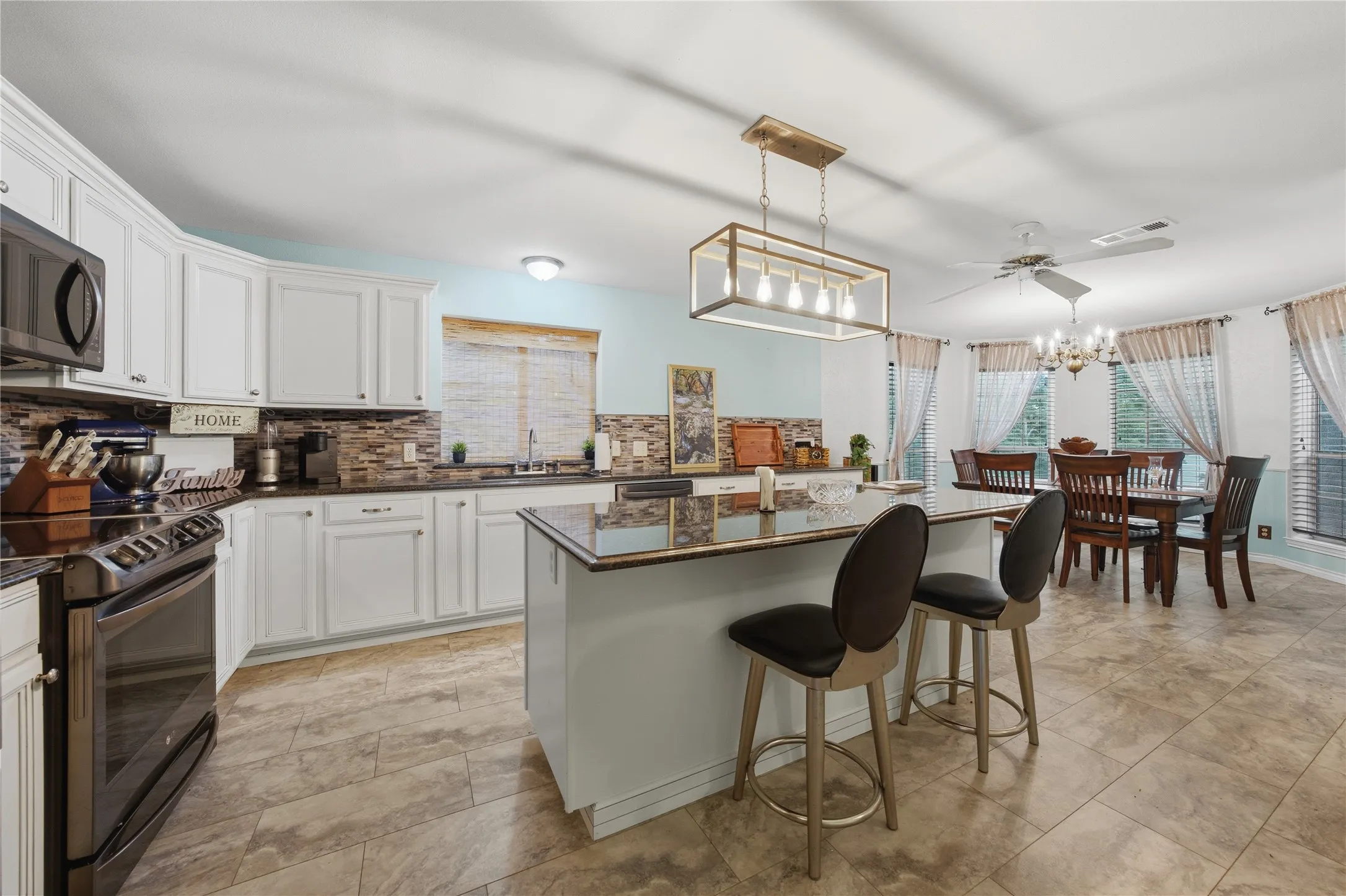 Spacious kitchen featuring white cabinetry, dark stone countertops, and a stone tile backsplash