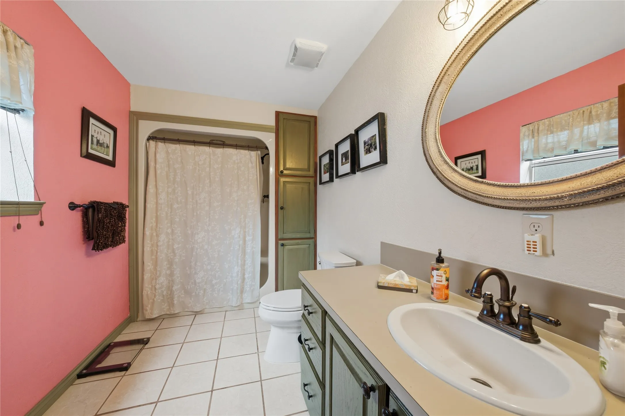 Bathroom featuring a vanity with an integrated sink, bronze-finish faucet, and a large ornate mirror