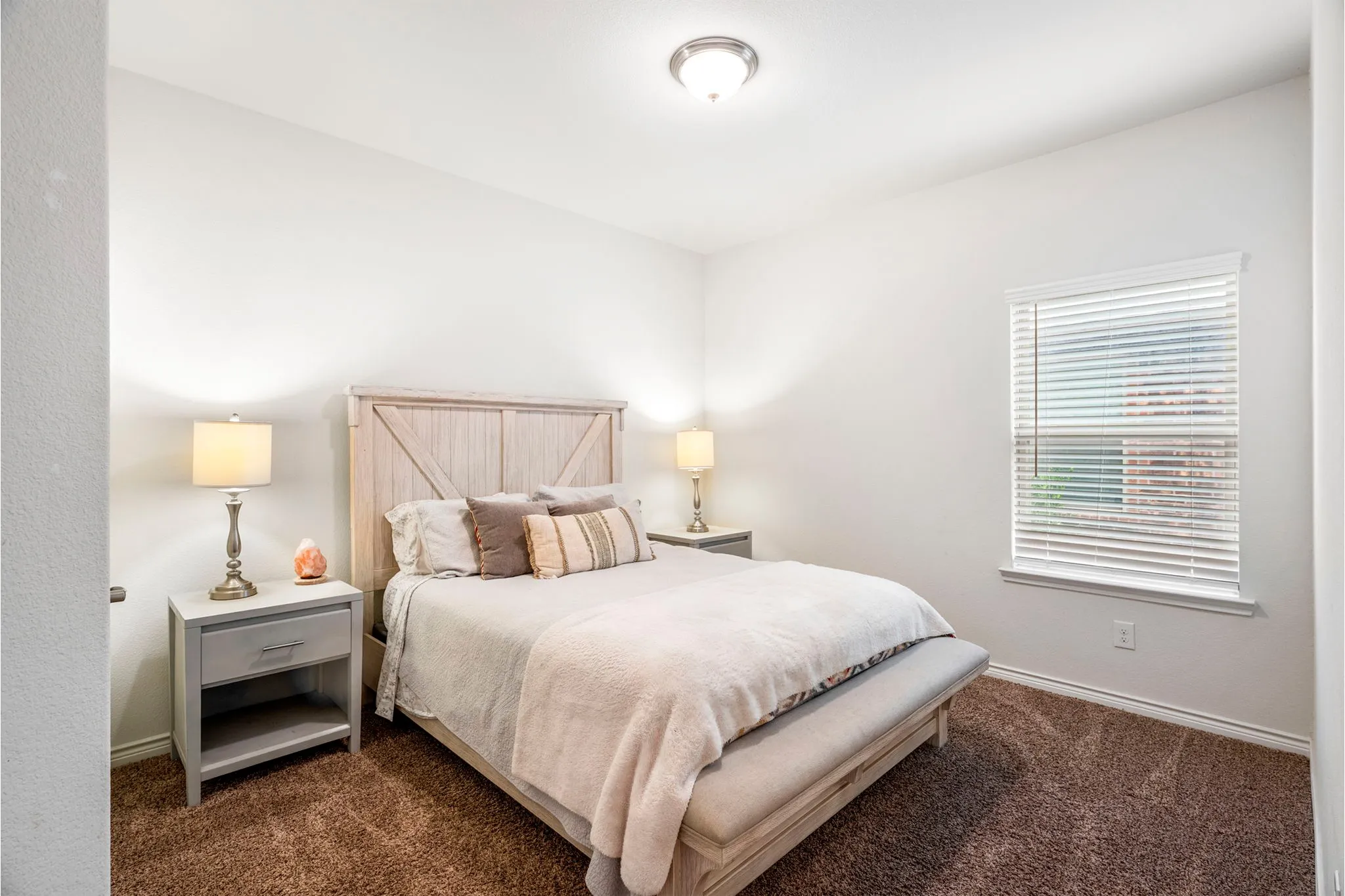Bedroom featuring a neutral color palette, brown carpet, and a window with blinds